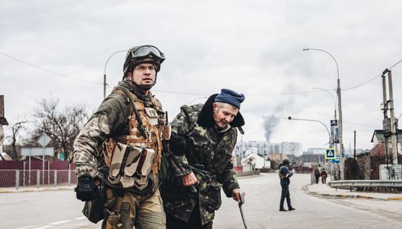 Un soldado ucraniano ayuda a un anciano en su escape de Irpín.