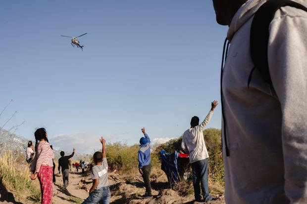 Migrantes saludan a un helicóptero del Departamento de Seguridad Pública de Texas tras cruzar la frontera en El Paso, Texas, el 2 de abril.