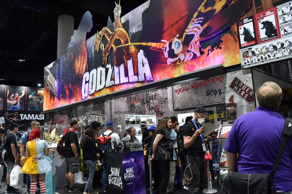 Los asistentes pasan por el stand de Bandai Godzilla durante la Comic-Con International en San Diego, California, el 26 de julio de 2025. (Foto de Chris DELMAS / AFP)