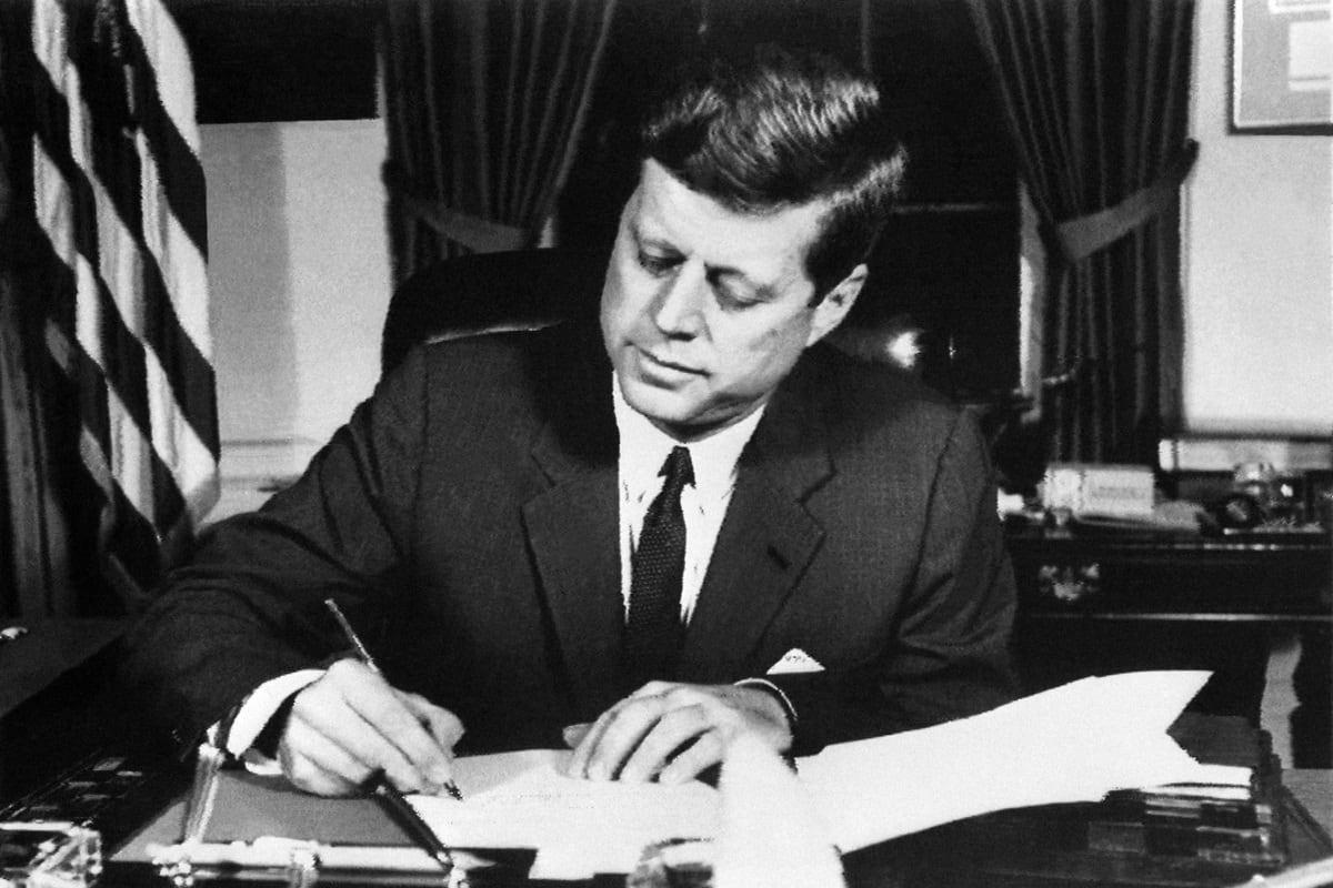 El presidente estadounidense John Fitzgerald Kennedy firma la orden de bloqueo naval a Cuba, el 23 de octubre de 1962 en la Casa Blanca, Washington DC, durante la crisis de los misiles cubanos. (Foto de AFP)
