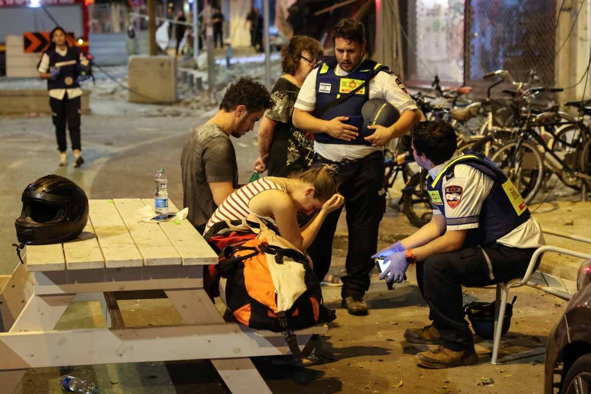 Una joven reacciona mientras habla con rescatistas israelíes en Tel Aviv, tras ser alcanzada por un cohete disparado por militantes palestinos desde la Franja de Gaza el 7 de octubre de 2023. El grupo militante palestino Hamás lanzó un ataque sorpresa a gran escala contra Israel el 7 de octubre, disparando miles de cohetes desde Gaza y enviando combatientes para matar o secuestrar personas, mientras Israel respondía con devastadores ataques aéreos. (Foto de JACK GUEZ / AFP)