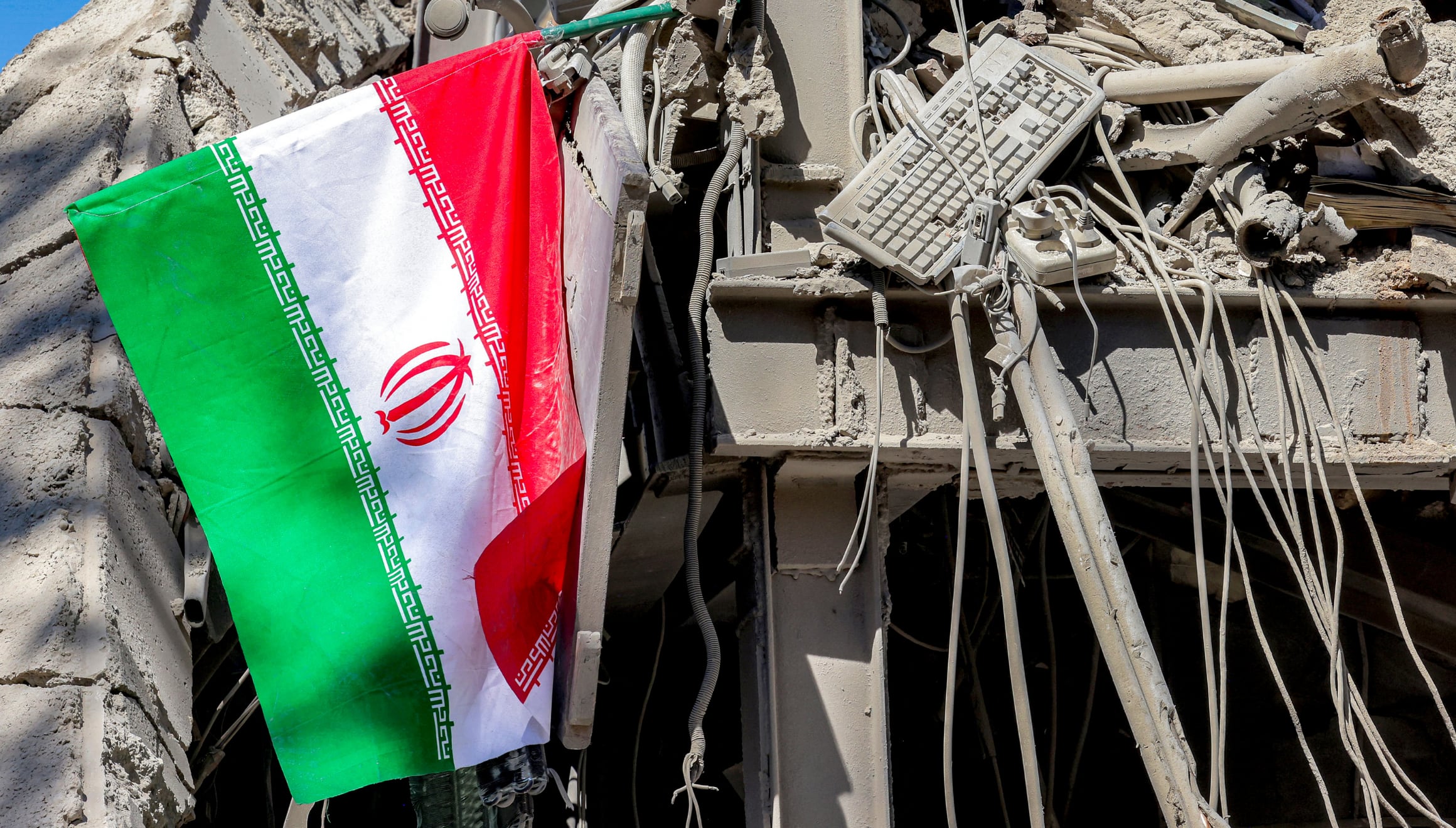Una bandera nacional iraní ondea entre los escombros de un edificio derrumbado tras los ataques a la Universidad Tecnológica Sharif en Teherán el 7 de abril de 2026. El suministro de gas se restableció el 6 de abril, después de haber sido interrumpido en algunas zonas de Teherán tras un ataque ocurrido en la madrugada contra una estación de reducción de presión de gas y las instalaciones de medición de la Universidad Tecnológica Sharif, lo que provocó una fuga. | Crédito: Atta Kenare / AFP