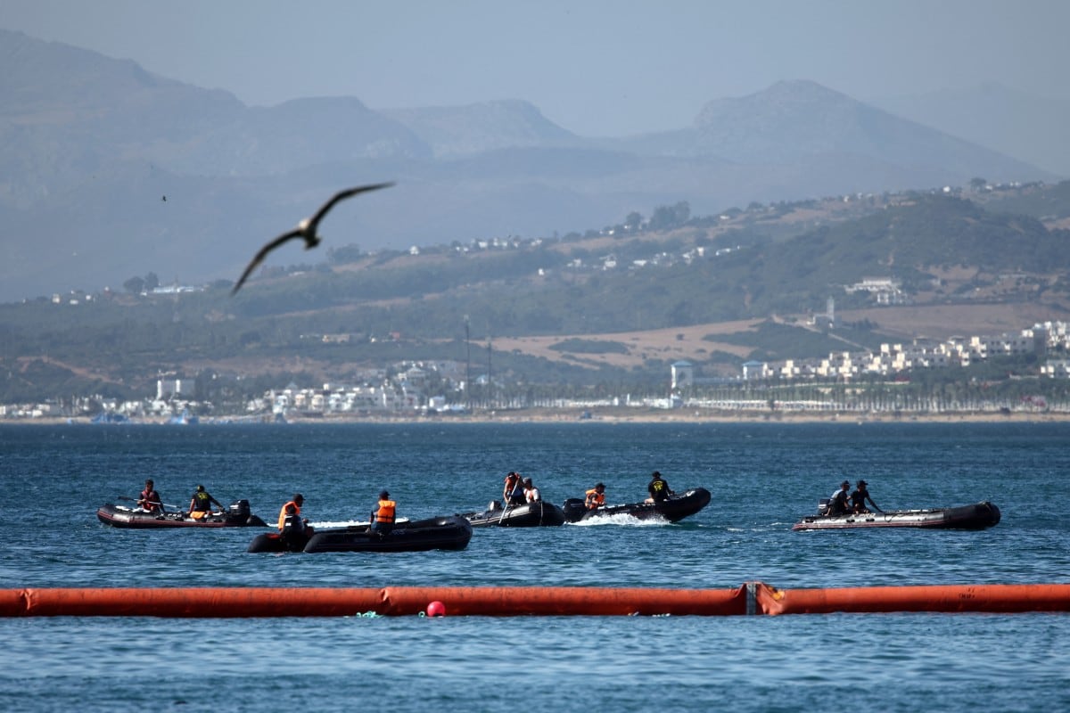 Varias personas a bordo de botes inflables navegan por el lado marroquí de la nueva barrera flotante desplegada por España para reforzar la seguridad cerca del puesto fronterizo del enclave español de Ceuta, el 2 de agosto de 2026. (Henry Nicholls / AFP)