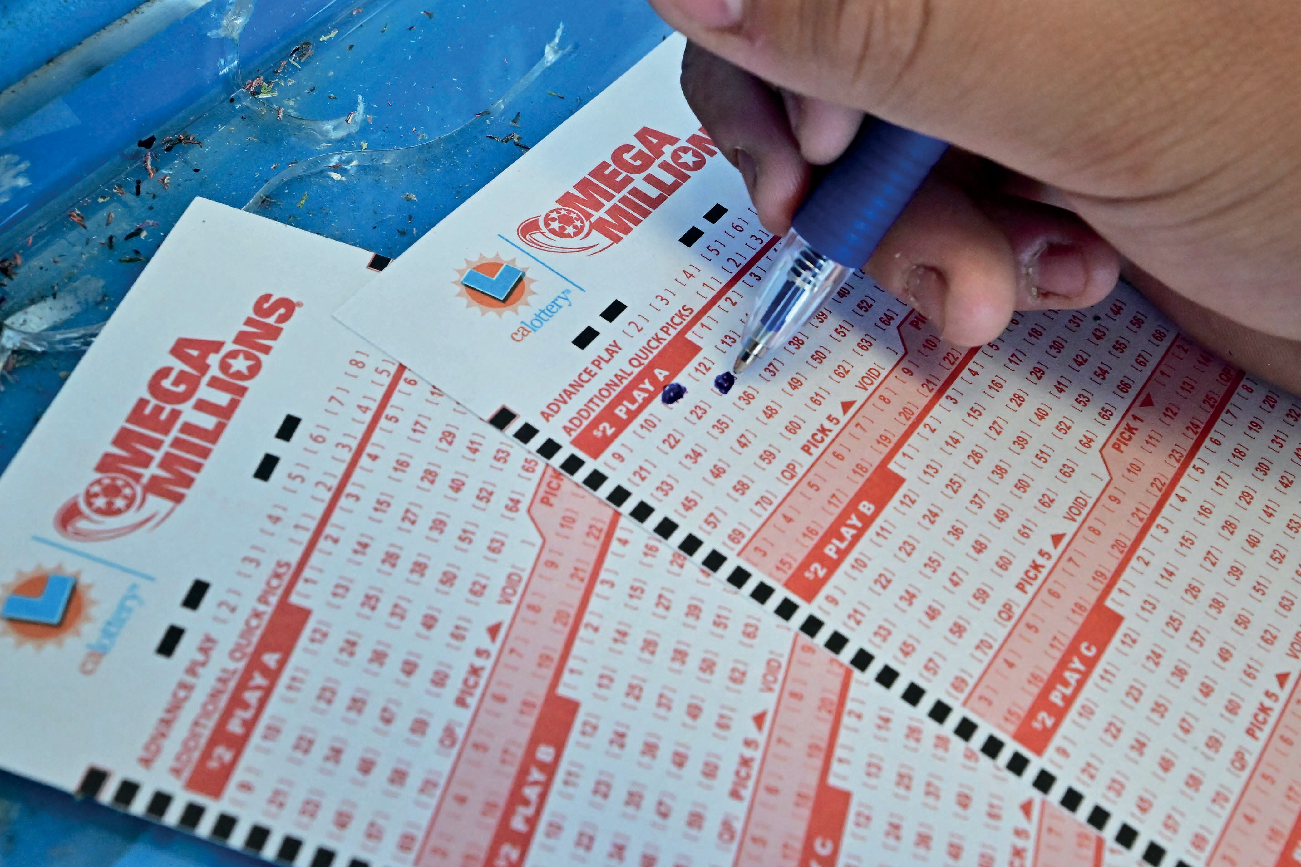 Un comprador selecciona los números en los boletos para la lotería Mega Millions en Los Ángeles, California, el 4 de agosto de 2023 (Foto: AFP)
