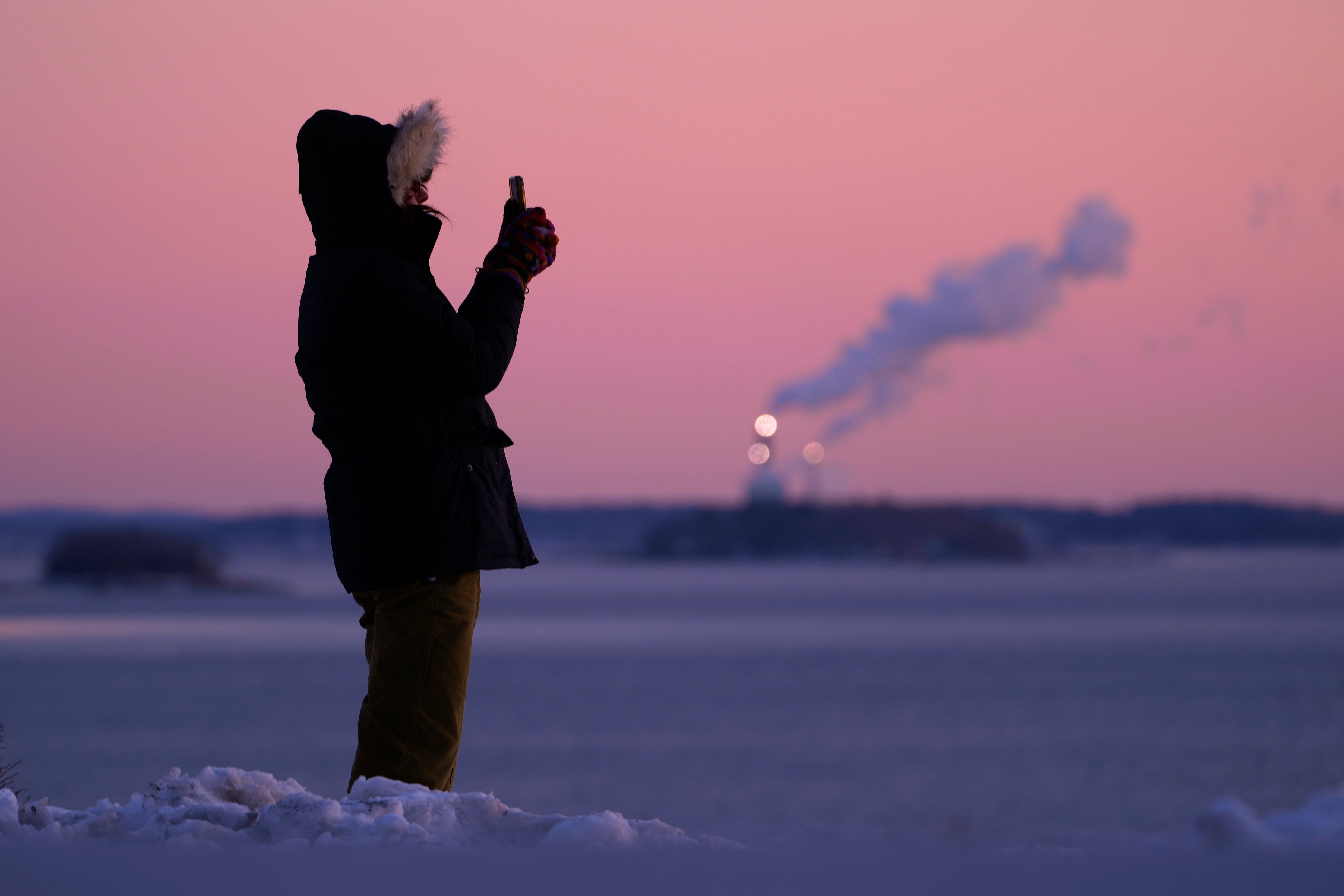 Una señorita tomando fotografía a la bahía de Casco durante la mañana del sábado 24 de enero 2026 en Portland, Maine. (AP Photo/Robert F. Bukaty)
