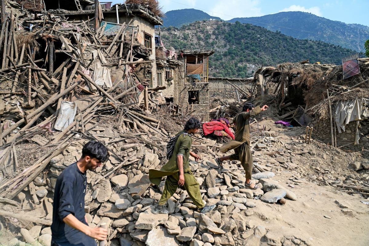 Afganos caminan junto a casas dañadas tras los terremotos ocurridos en la aldea de Mazar Dara, en el distrito de Nurgal, provincia de Kunar, en el este de Afganistán, el 1 de septiembre de 2025. Foto: Wakil Kohsar / AFP