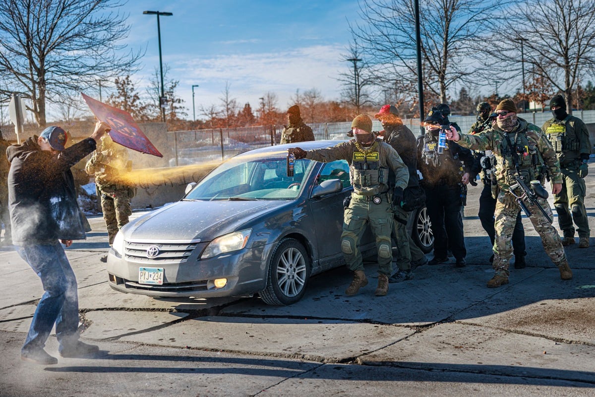 Agentes federales usan gas pimienta contra un manifestante que sostiene un cartel durante una operación policial frente al edificio Whipple, instalación de ICE en Minneapolis, Minnesota, el 11 de enero de 2026. (Kerem YUCEL / AFP)