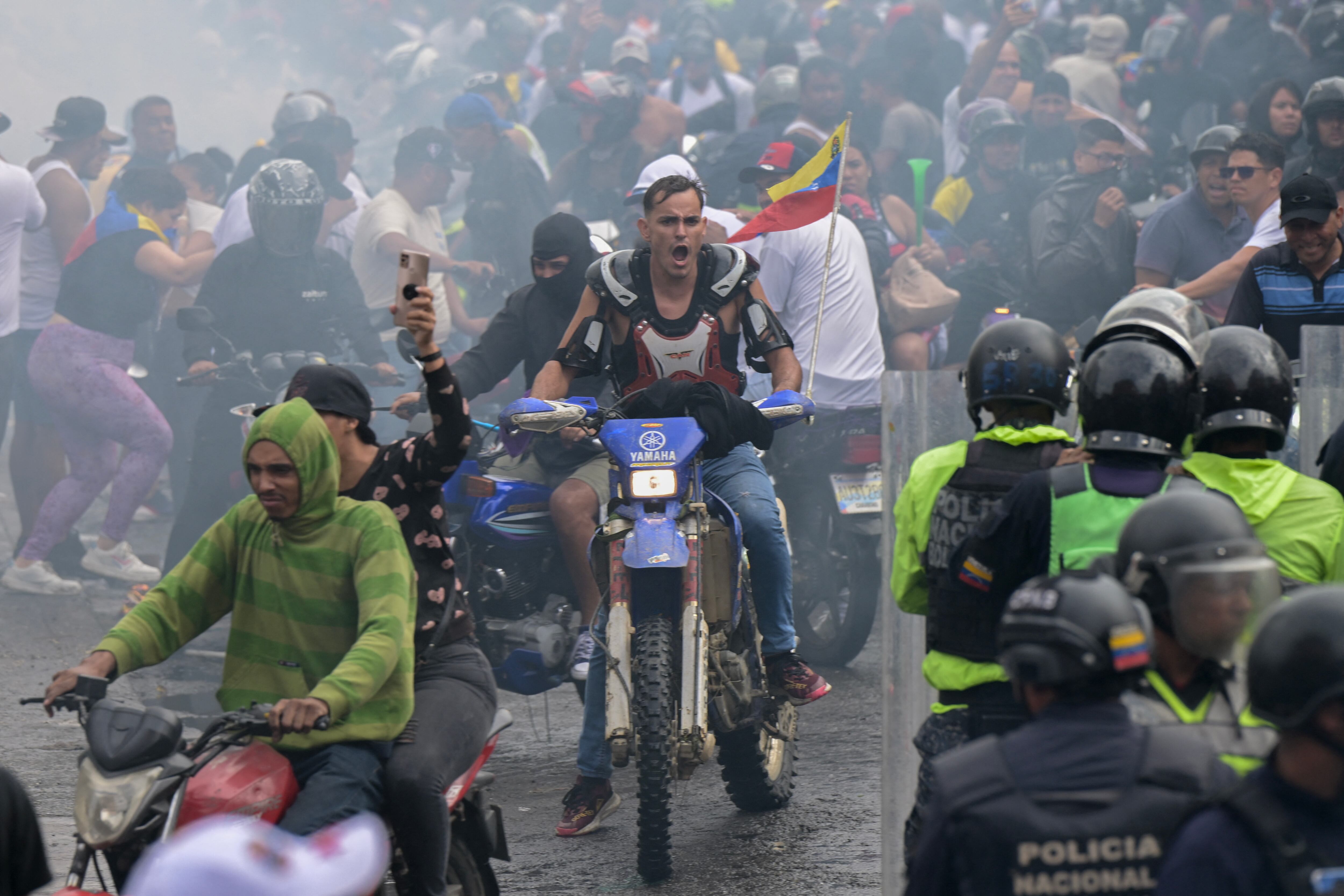 Venezuela: Los manifestantes huyen de los gases lacrimógenos durante una protesta contra el gobierno del presidente Nicolás Maduro en Caracas el 29 de julio de 2024. (Foto de Yuri CORTEZ / AFP).