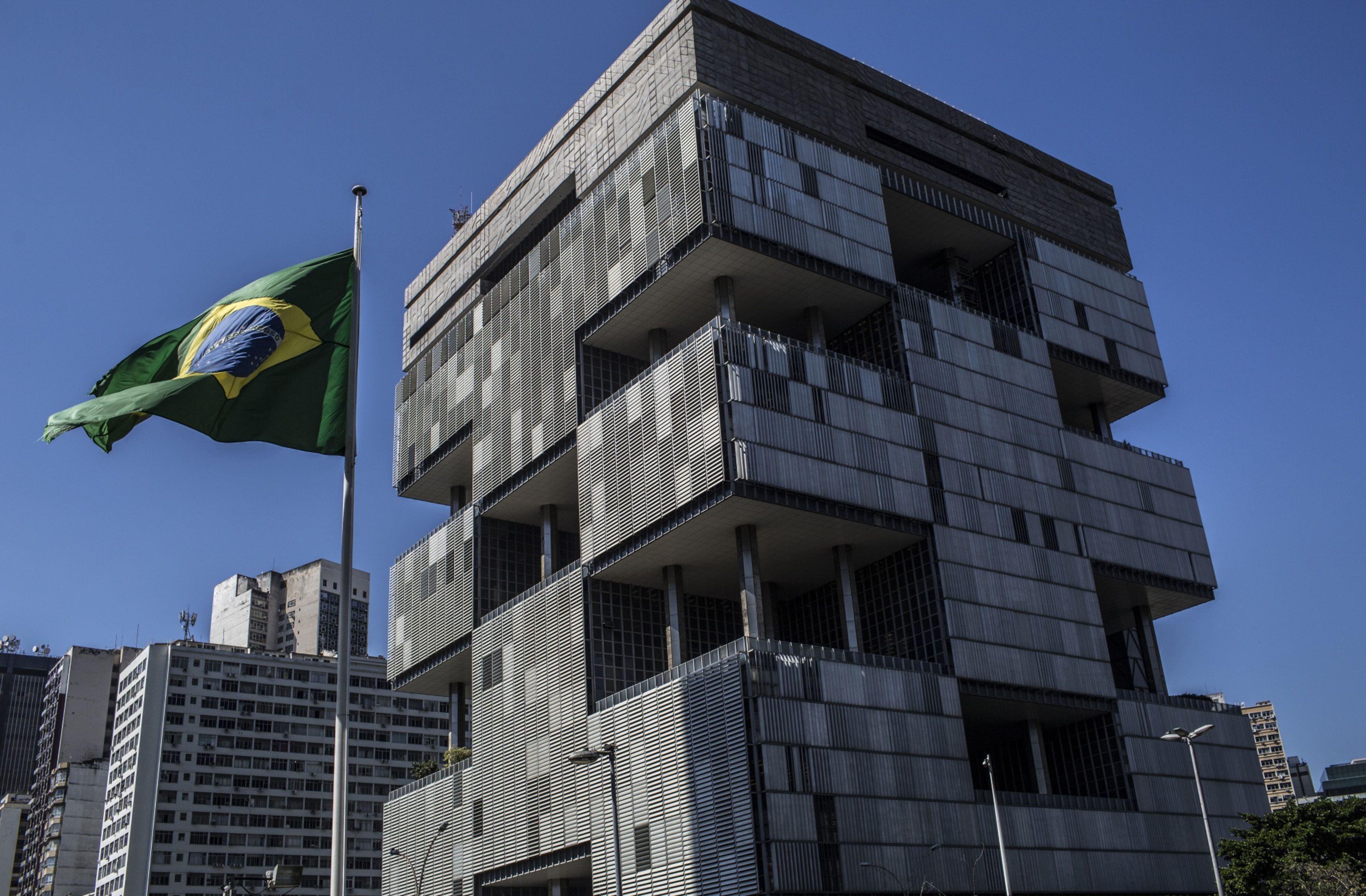 A Brazilian flag flies outside Petroleo Brasileiro SA (Petrobras) headquarters in Rio de Janeiro, Brazil, on Monday, July 29, 2018. Jose Salim Mattar, the ministry of economy's privatizer-in-chief, is on a mission to sell over 100 state-controlled companies from electricity generators to the postal service to the government's crown jewels -- the nation's largest public enterprises including Petrobras.