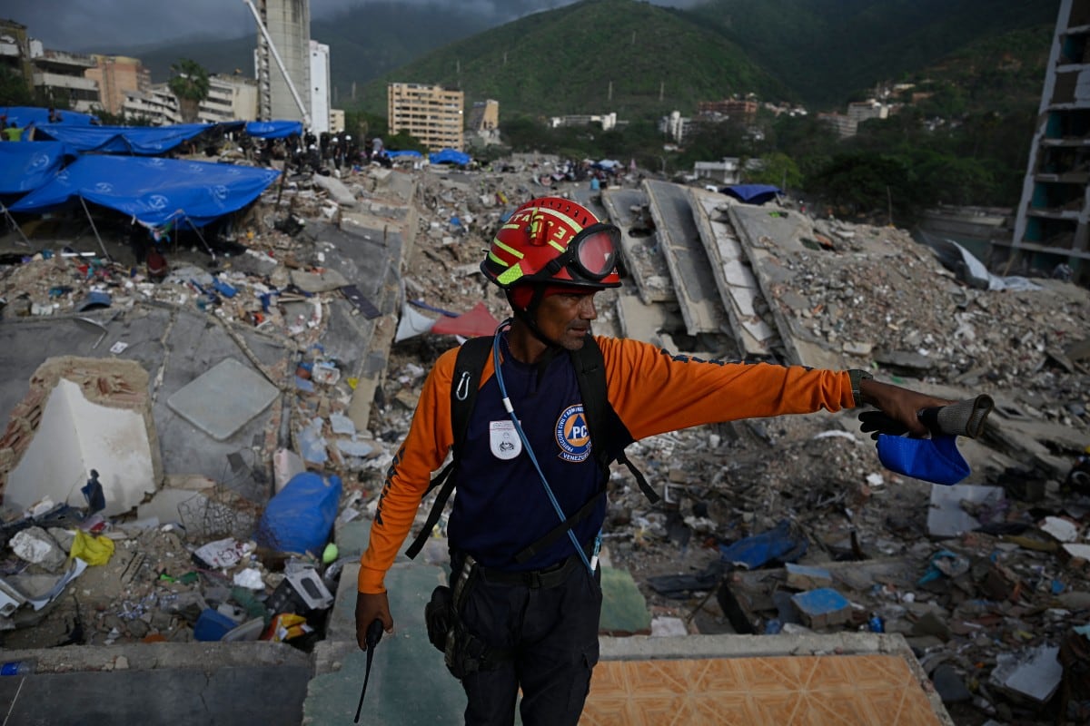 Un miembro del servicio de Protección Civil participa en la búsqueda de cuerpos entre los escombros de un edificio derrumbado en Caraballeda, Venezuela, el 23 de julio de 2026, casi un mes después de los terremotos del 24 de junio. (Federico PARRA / AFP)