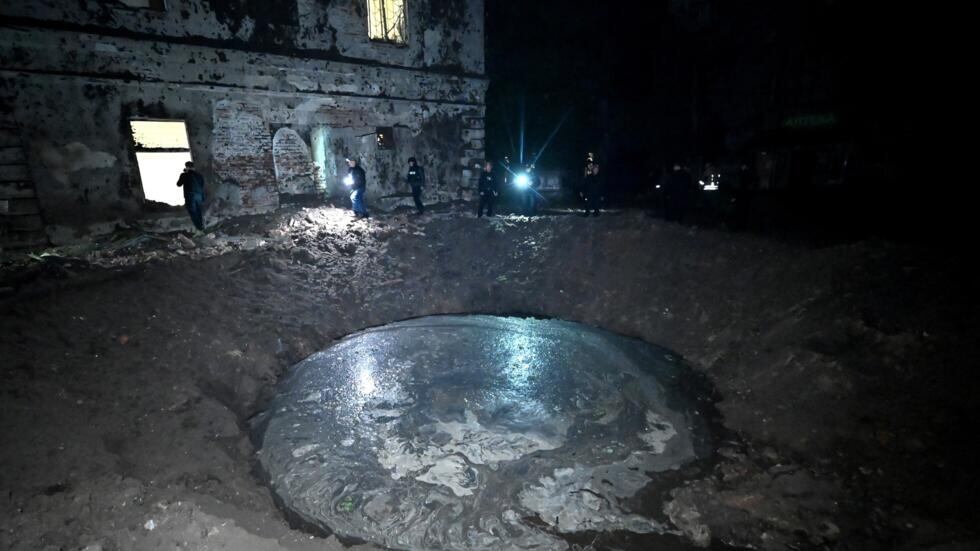 Agentes de las fuerzas de seguridad inspeccionan el cráter abierto junto a un edificio. Foto: AFP