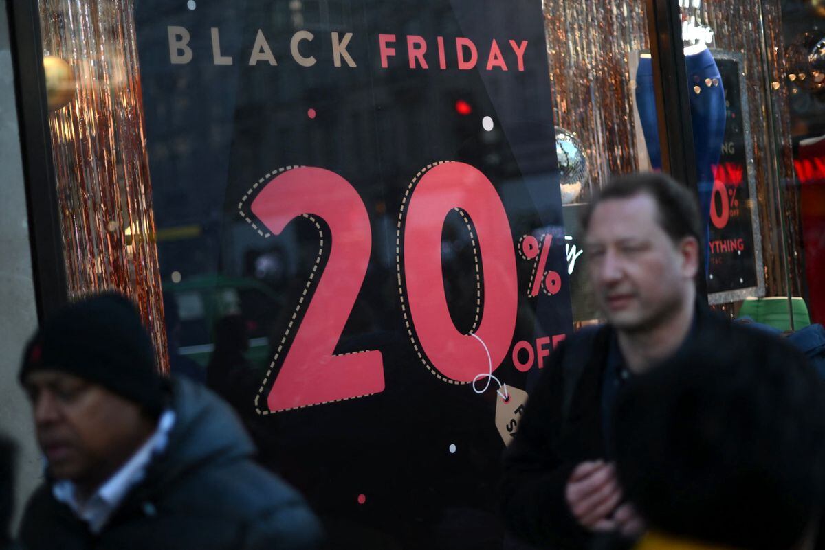 Los compradores pasan escaparates que anuncian ventas con descuento del Viernes Negro (Foto: Daniel Leal / AFP)