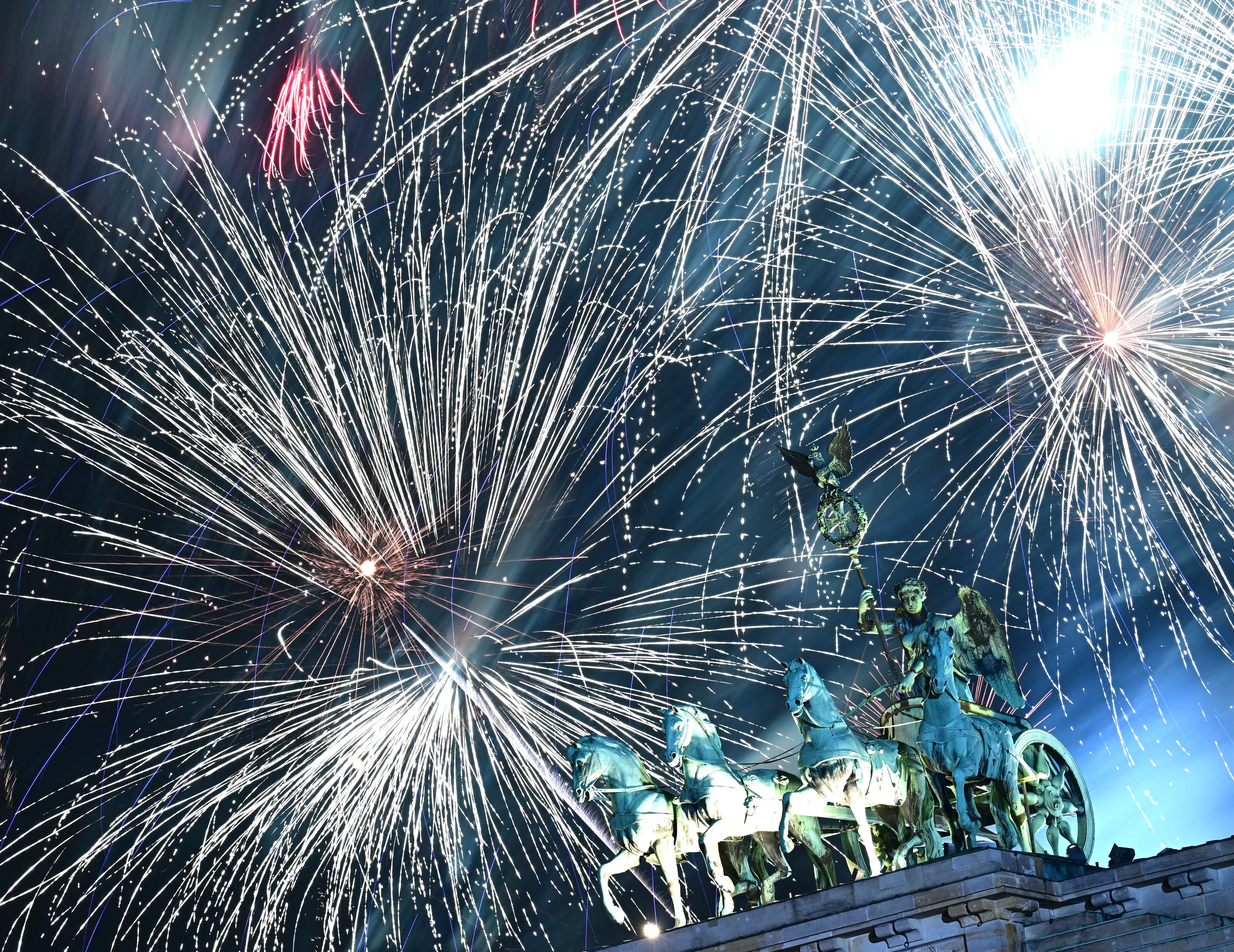 Los fuegos artificiales iluminan la Cuadriga en lo alto de la Puerta de Brandeburgo durante las celebraciones del Año Nuevo en Berlín el 1 de enero de 2025. (Foto de Tobias SCHWARZ / AFP).