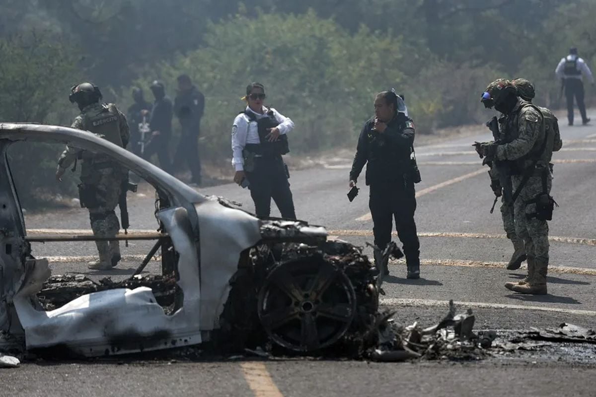 Integrantes de la policía de Morelia y del ejército trabajan en la zona donde fue incendiado un vehículo por presuntos integrantes del crimen organizado en Morelia. Foto: EFE/ Iván Villanueva