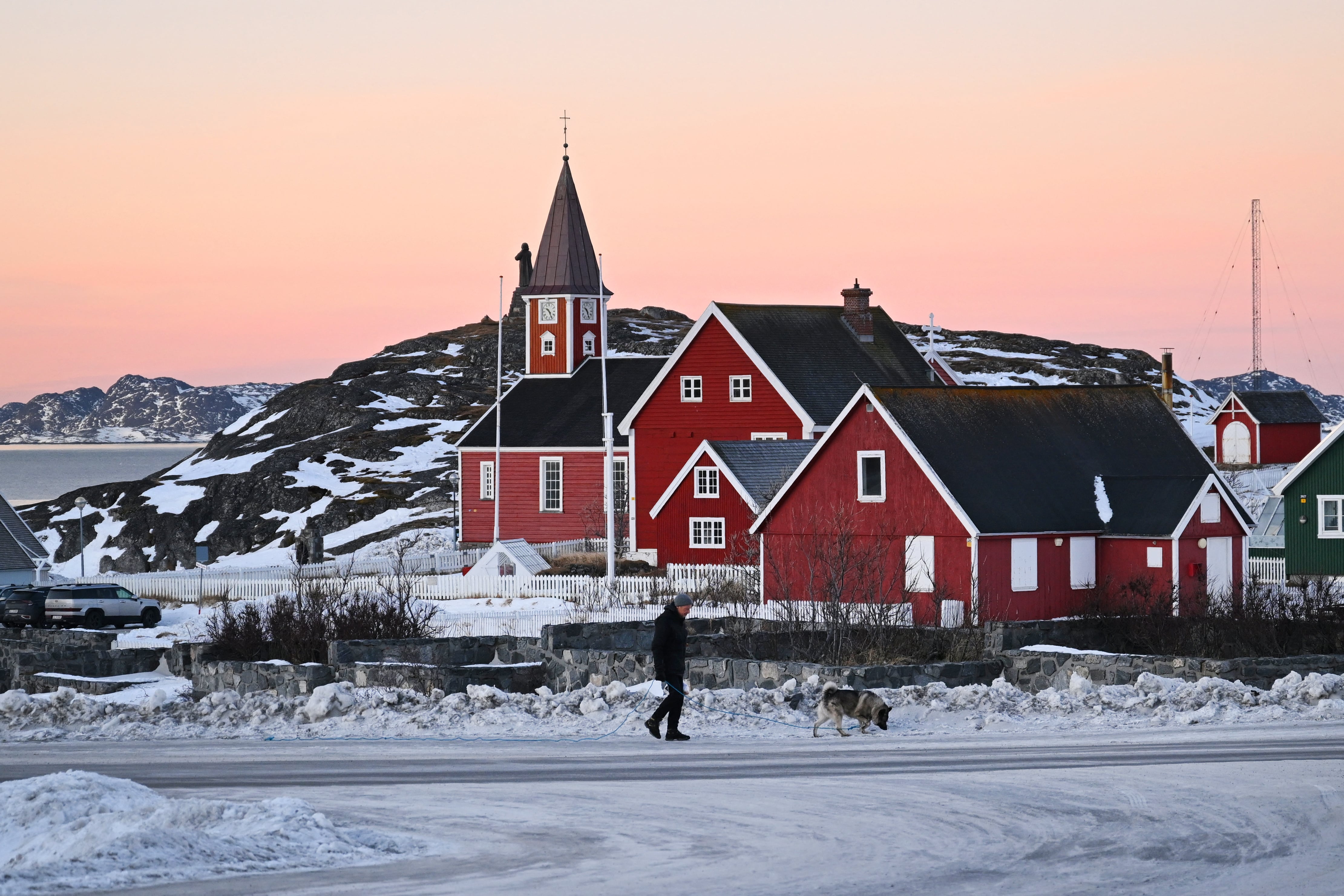Un hombre pasea con su perro frente a una iglesia en la ciudad de Nuuk, en el oeste de Groenlandia, el 27 de enero de 2026. (Foto de Ina FASSBENDER / AFP).