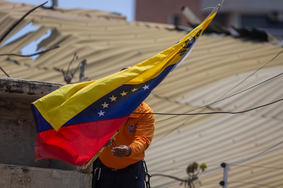 Un integrante de la Protección Civil de Venezuela coloca una bandera en una zona afectada por terremotos este martes, en La Guaira (Venezuela). Foto: EFE/ Miguel Gutiérrez