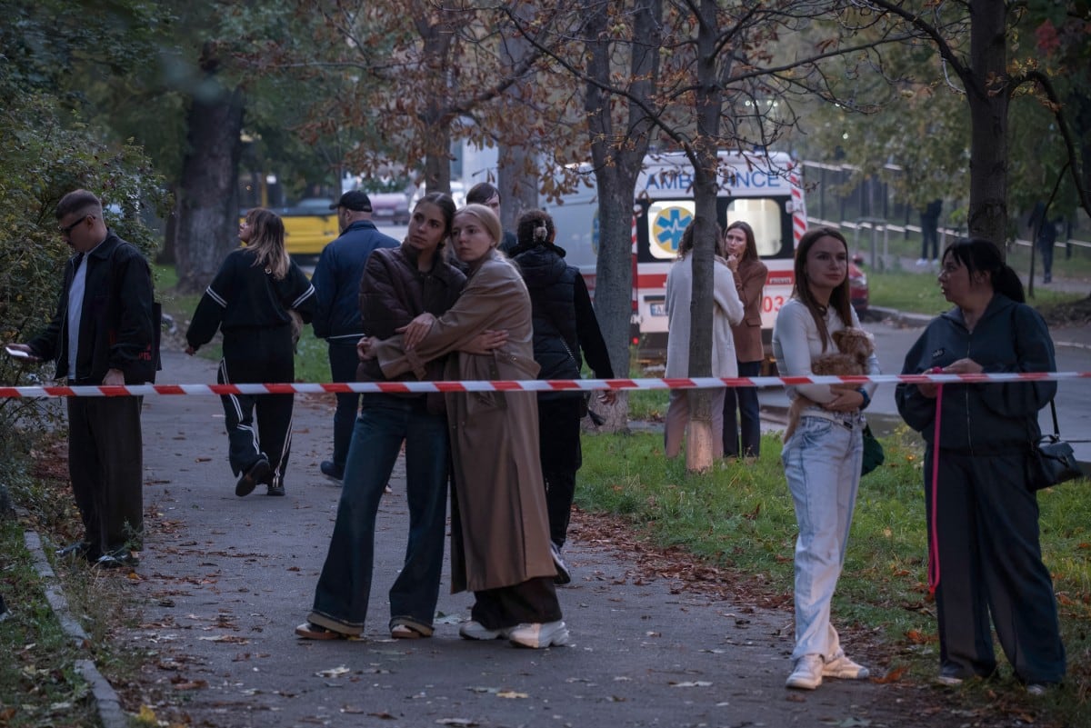 Residentes locales aguardan tras la cinta de seguridad mientras los equipos de rescate trabajan en un edificio residencial de cinco plantas dañado tras un ataque con drones rusos en Kiev el 7 de octubre de 2026, en el contexto de la invasión rusa de Ucrania. (Foto de Vladyslav Musiienko / AFP)