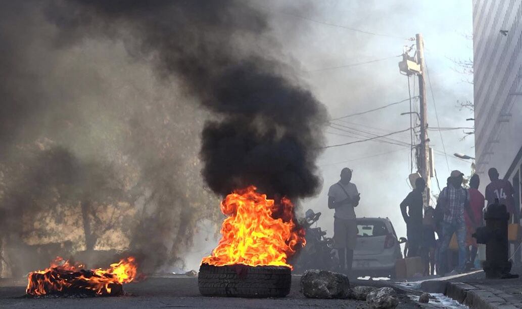 This screen grab taken from AFPTV shows tires on fire near the main prison of Port-au-Prince, Haiti, on March 3, 2024, after a breakout by several thousand inmates. At least a dozen people died as gang members attacked the main prison in Haiti's capital, triggering a breakout by several thousand inmates, an AFP reporter and an NGO said on March 3. "We counted many prisoners' bodies," said Pierre Esperance of the National Network for Defense of Human Rights, adding that only around 100 of the National Penitentiary's estimated 3,800 inmates were still inside the facility after the gang assault overnight on March 2. (Photo by Luckenson JEAN / AFPTV / AFP)