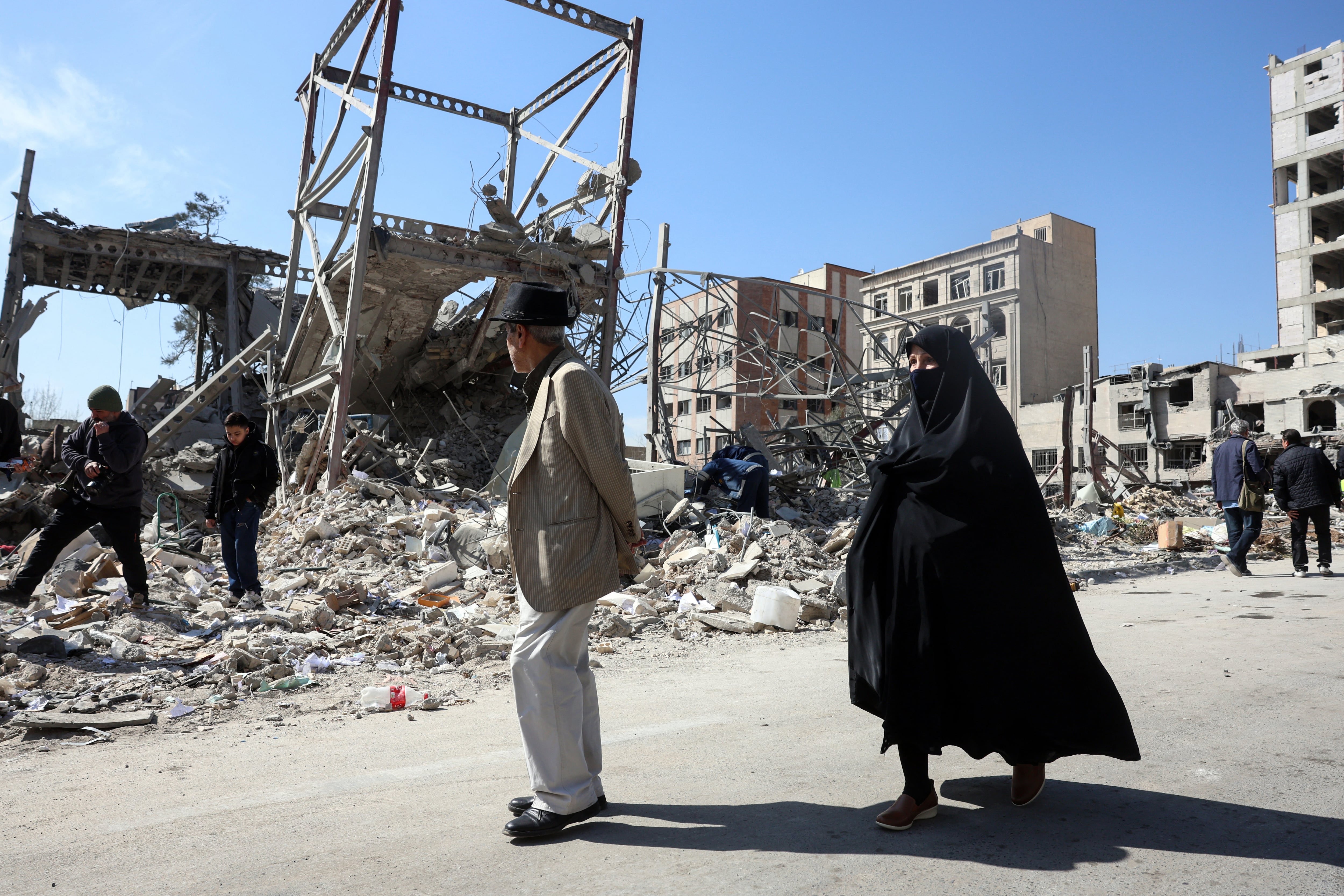 Un hombre y una mujer caminan junto a edificios destruidos tras los ataques aéreos en el centro de Teherán, Irán, el 4 de marzo de 2026. (Foto de AFP).