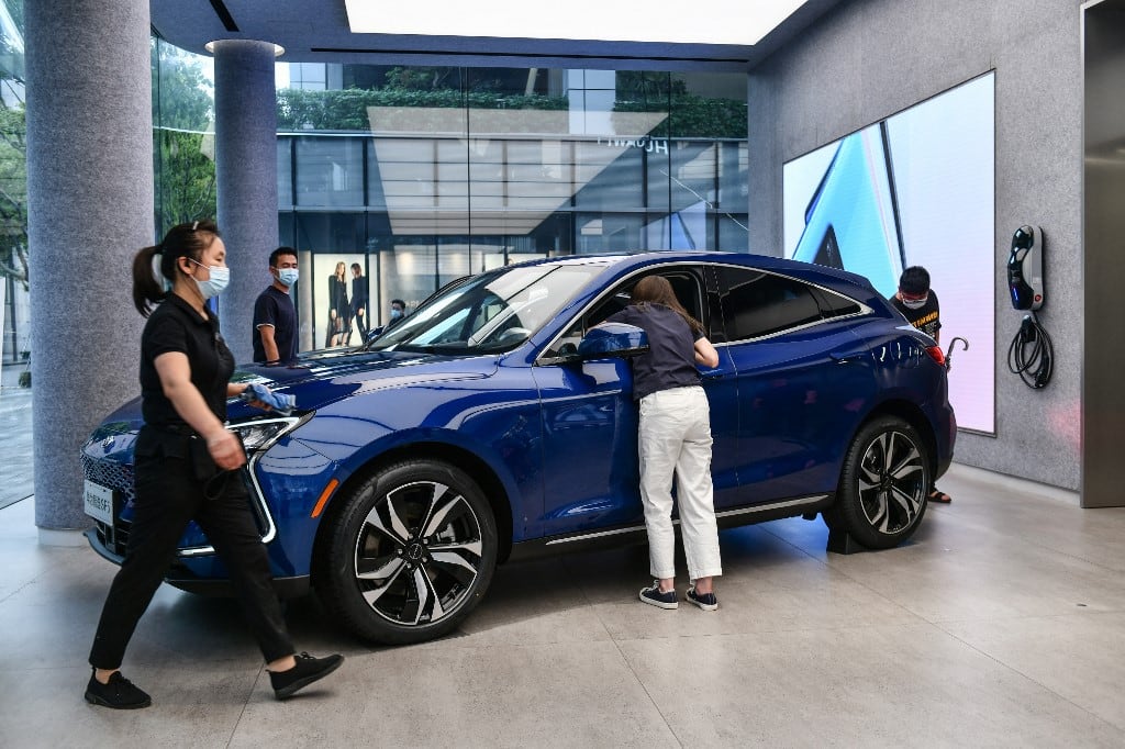 Esta foto, tomada el 31 de mayo de 2021, muestra a personas observando un SUV Huawei Seres SF5 en la tienda insignia de Huawei en Shenzhen, en la provincia de Guangdong, al sur de China. (Foto de CN-STR / AFP)