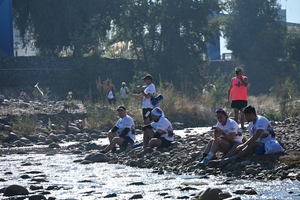 Corredores descansan junto al río Mapocho tras participar en una carrera a lo largo de sus orillas en Santiago, el 17 de mayo de 2026. (Foto de RODRIGO ARANGUA / AFP)