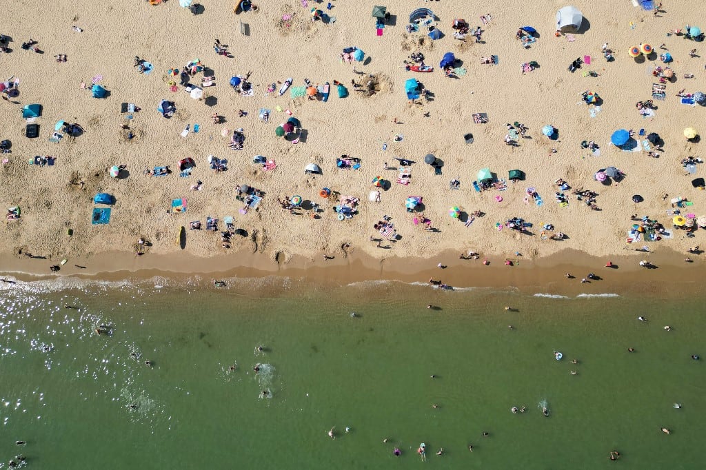 Una fotografía aérea muestra a personas jugando en el mar y relajándose bajo el sol en la playa de Bournemouth, en la costa sur de Inglaterra, el 26 de mayo de 2026, mientras la ola de calor se extendía por el sureste de Inglaterra y Londres. El martes, Gran Bretaña registró la temperatura más alta jamás registrada en mayo, alcanzando los 35 °C cerca de la capital. (Foto de JUSTIN TALLIS / AFP)