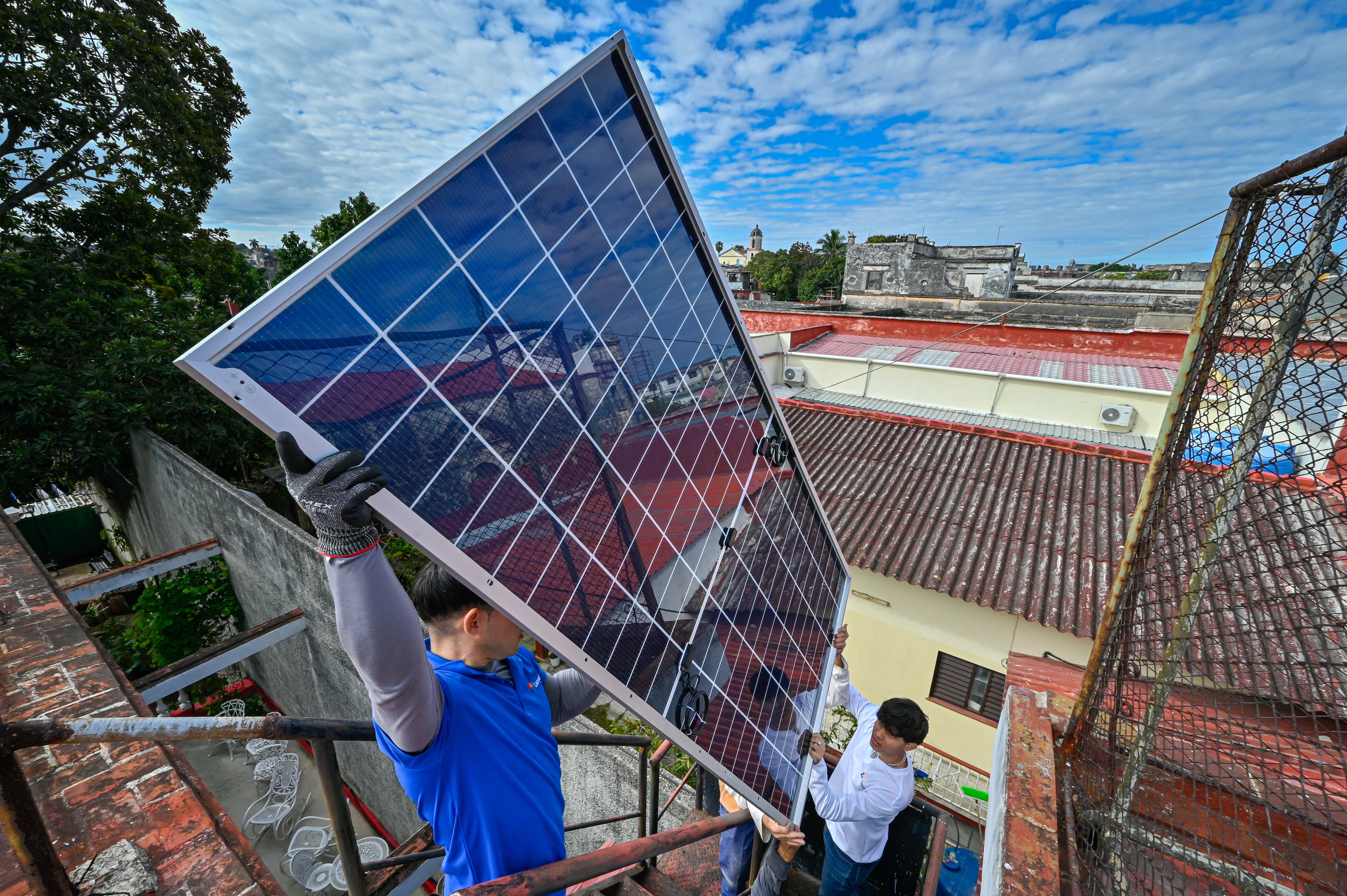 Un equipo de instaladores de sistemas fotovoltaicos instala paneles en el tejado de un comedor para ancianos administrado por una iglesia católica en el barrio de Guanabacoa, La Habana, el 4 de febrero de 2026. (Foto de ADALBERTO ROQUE / AFP).