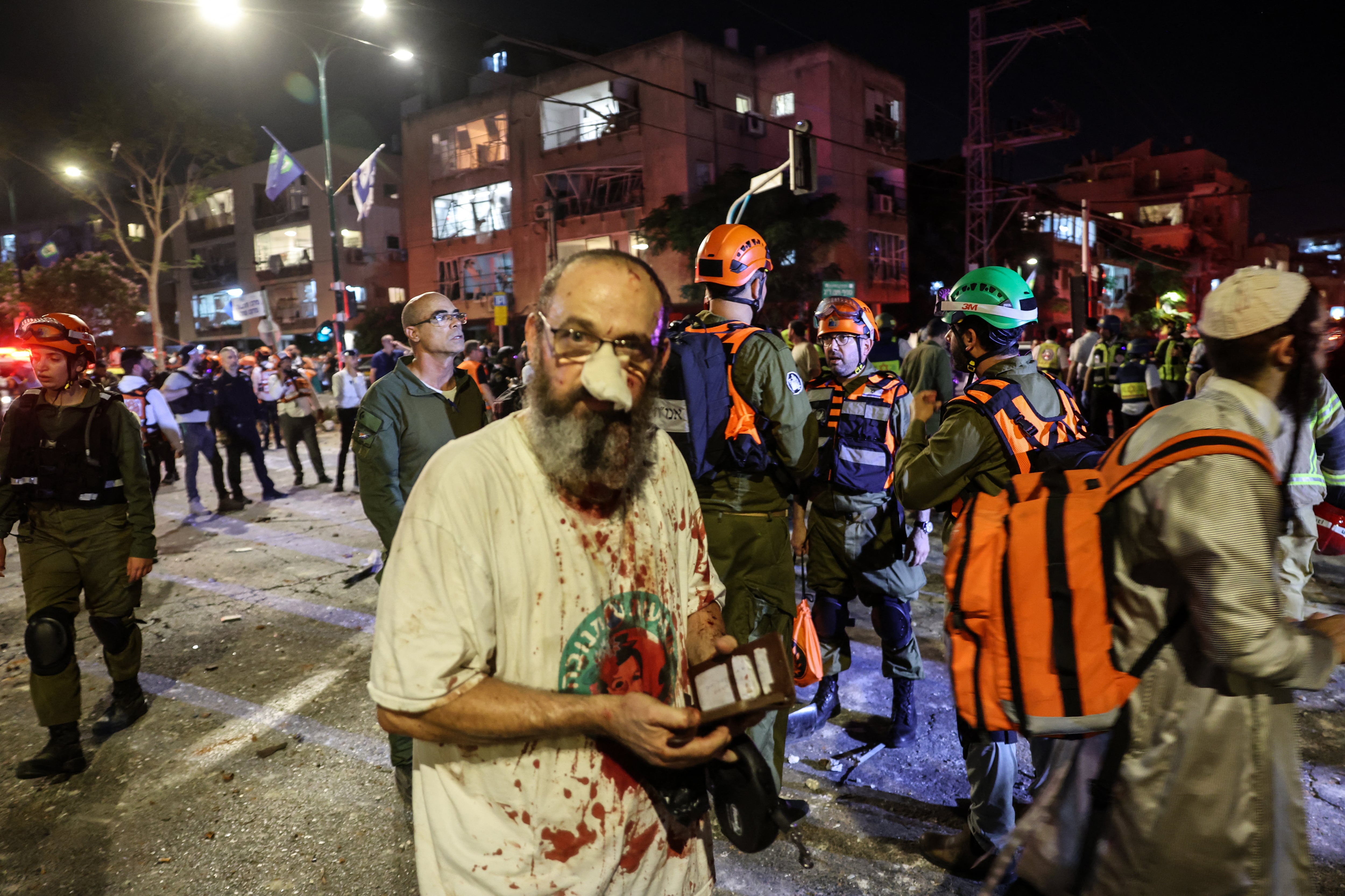 Un hombre herido se encuentra entre los socorristas en una zona impactada por un misil lanzado desde Irán, en Ramat Gan, cerca de Tel Aviv, el 13 de junio de 2025. (Foto de Jack GUEZ / AFP)