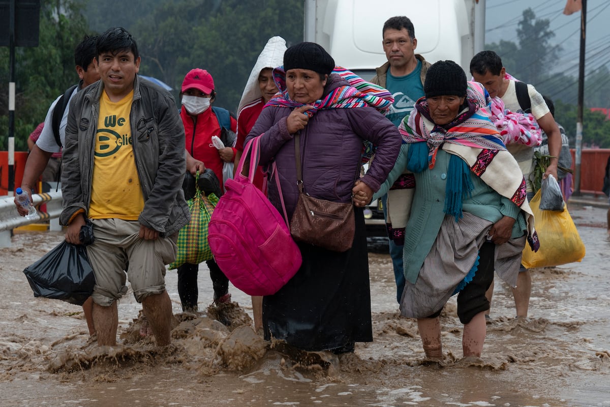 Las personas caminan en el agua que inunda la Carretera Central luego de fuertes lluvias en Chaclacayo.