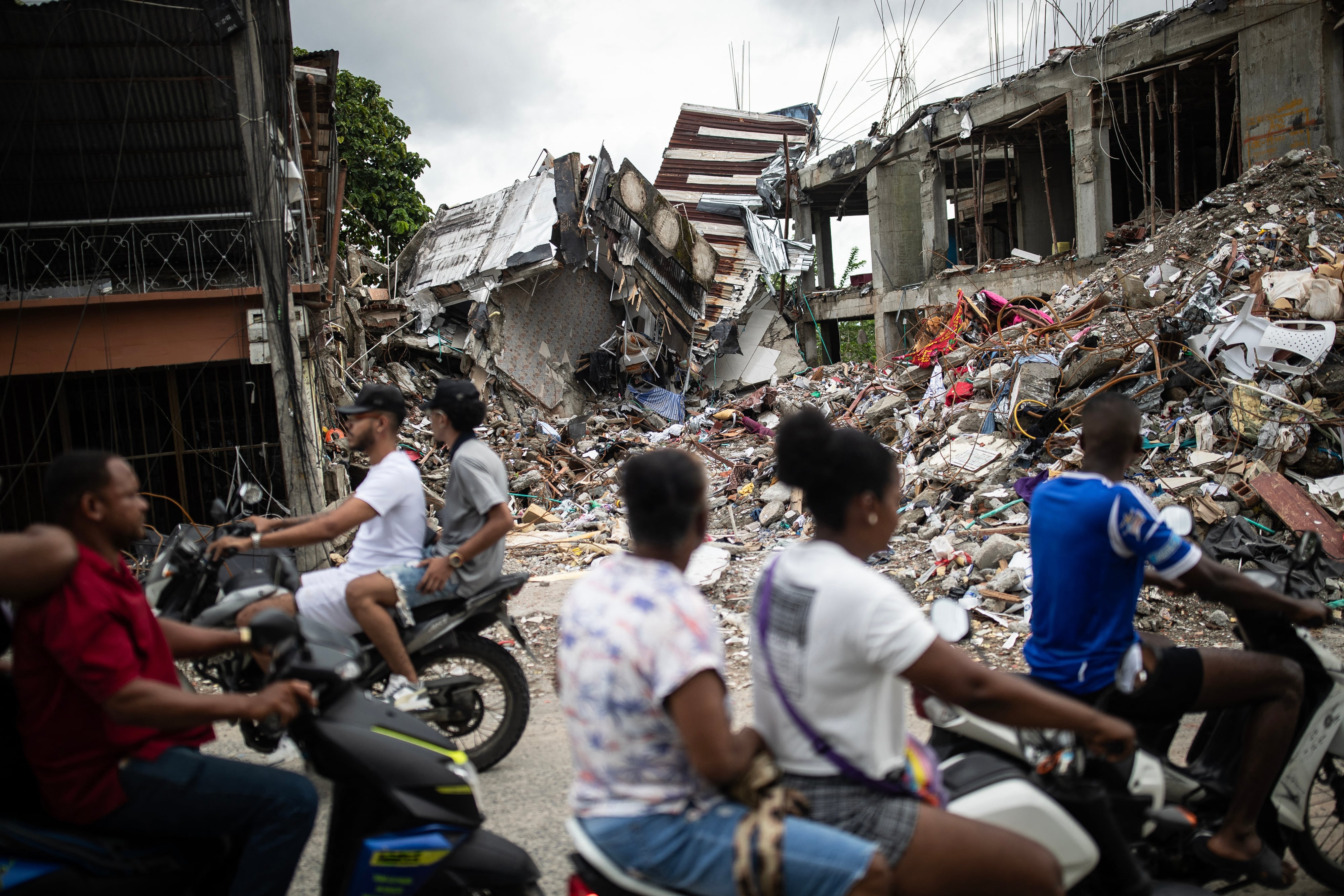 Personas en motocicletas pasan frente a un edificio destruido en el barrio Medrano de Quibdó, departamento del Chocó, Colombia, el 15 de agosto de 2026, días después del terremoto de magnitud 7.4. (Foto de ESTEBAN VEGA LA-ROTTA / AFP).