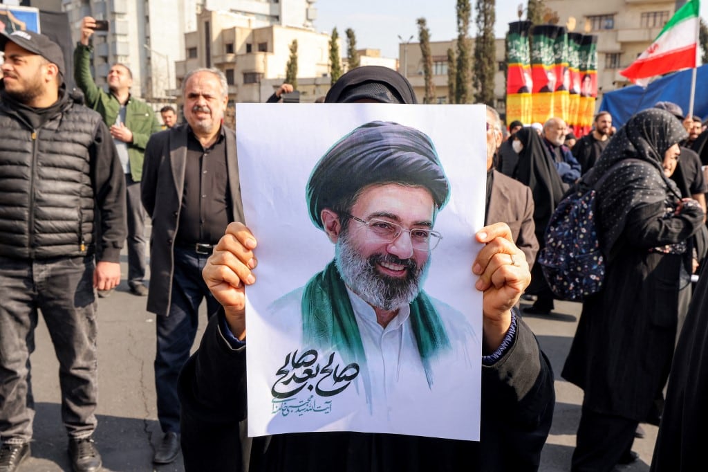 Una mujer posa con una foto del nuevo líder supremo de Irán, el ayatolá Mojtaba Jamenei, durante una manifestación en su apoyo en la plaza Enghelab, en el centro de Teherán, el 9 de marzo de 2026. Irán celebró el nombramiento del ayatolá Mojtaba Jamenei como líder supremo en reemplazo de su padre con una nueva andanada de misiles contra Israel y los países del Golfo el lunes, mientras la guerra en Oriente Medio disparaba los precios del petróleo. (Foto de Atta KENARE / AFP)