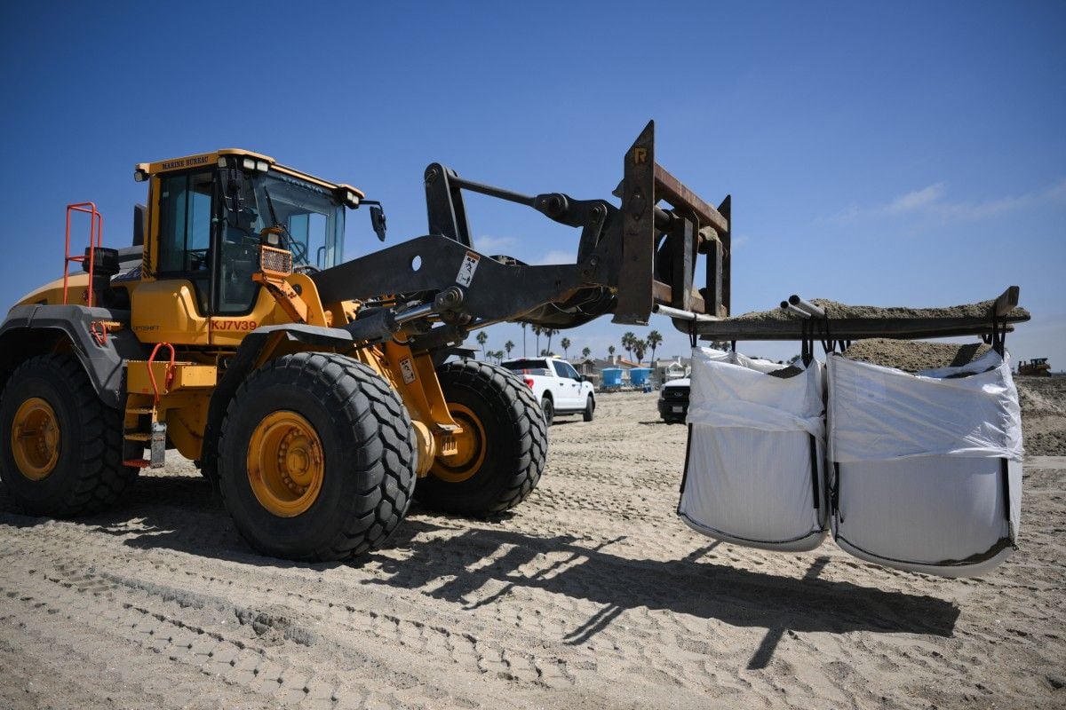 Una cargadora de ruedas traslada grandes sacos de arena antes de que sean colocados para proteger las viviendas del fuerte oleaje, las inundaciones costeras y la erosión de la playa ante la llegada del huracán Polo a Long Beach, California, el 24 de septiembre de 2026 (Foto: Patrick T. Fallon / AFP)