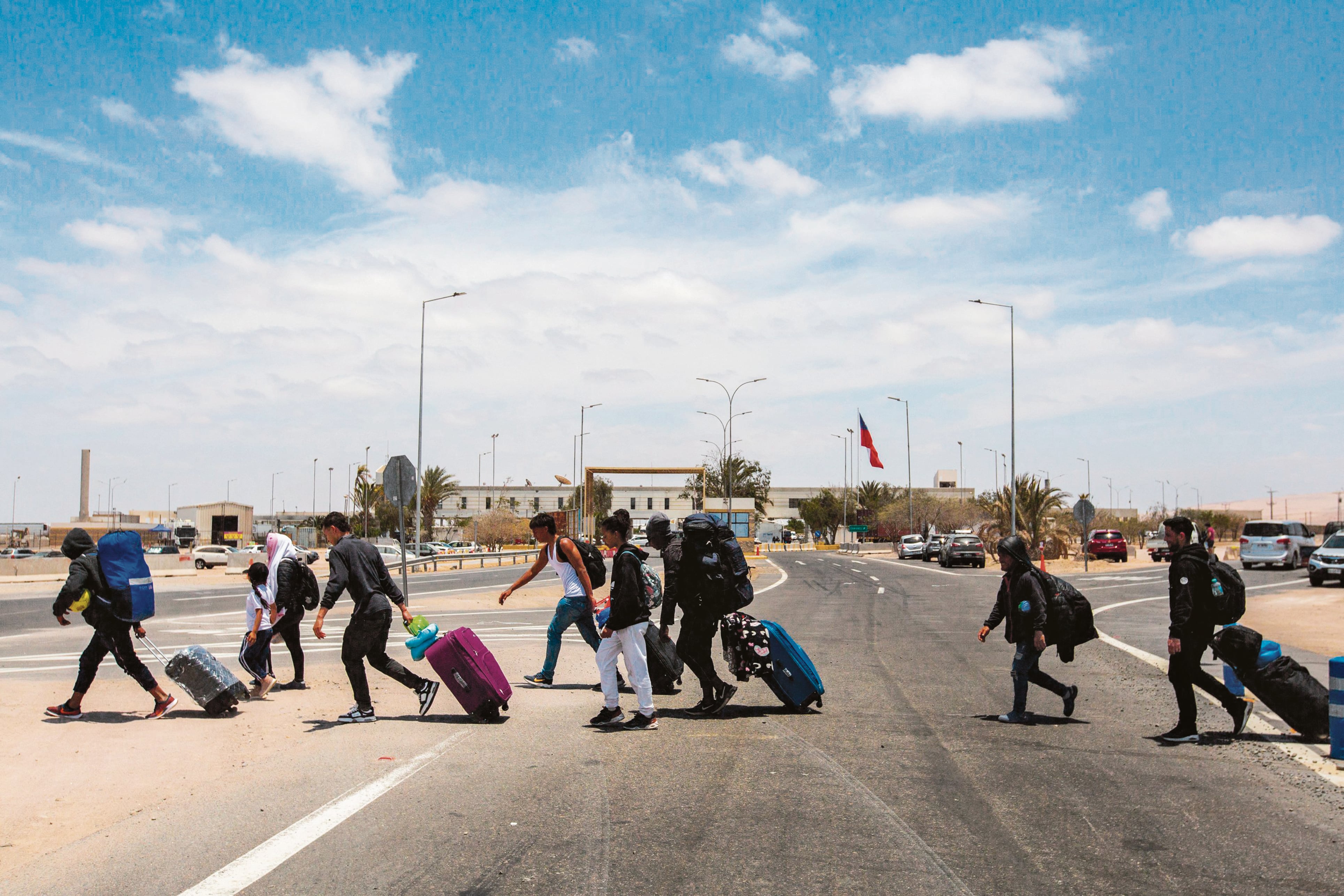 Migrantes caminan cerca del cruce fronterizo de Cachalluta con Perú, a unos 25 km al norte de Arica, Chile, el 28 de noviembre de 2025. Decenas de migrantes que buscaban salir de Chile quedaron varados en la frontera con Perú, informaron las autoridades el viernes, en medio de los temores generados por la amenaza del candidato presidencial chileno de extrema derecha, José Antonio Kast, de expulsar a los migrantes indocumentados. (Foto de Patricio BANDA / AFP)