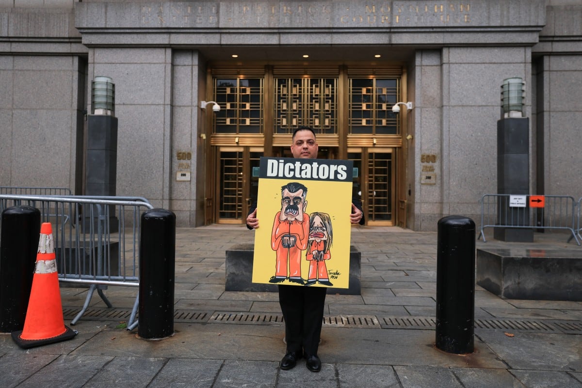 Un manifestante sostiene un cartel con una ilustración del derrocado presidente venezolano Nicolás Maduro y su esposa Cilia Flores, frente al Tribunal Federal Daniel Patrick Moynihan en la ciudad de Nueva York, el 22 de julio de 2026. (Foto de TIMOTHY A. CLARY / AFP)