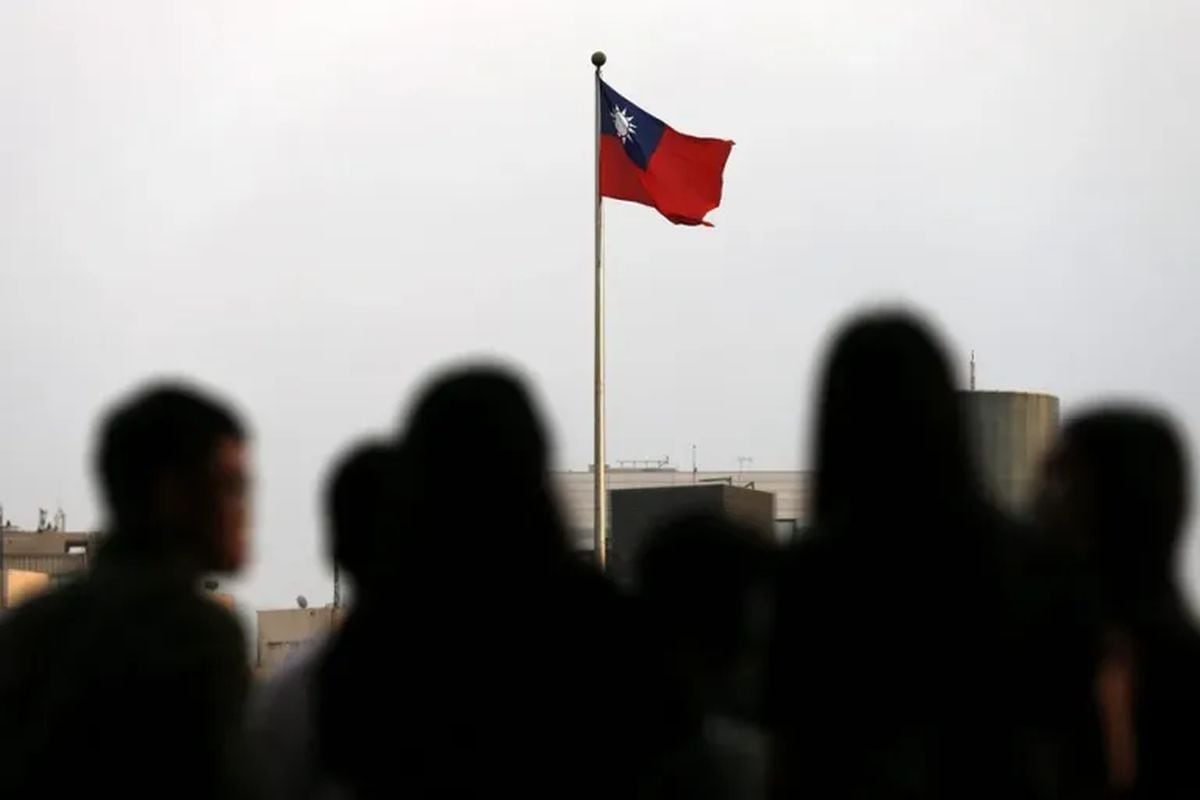 Fotografía de archivo de personas pasando frente a una bandera taiwanesa, en Taipei (Taiwán). Foto: EPA/ Ritchie B. Tongo.