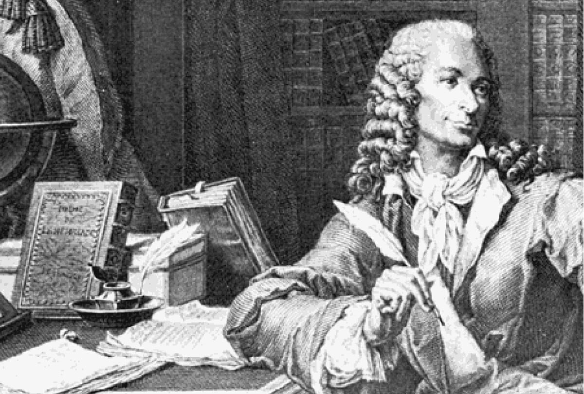 Voltaire en su escritorio con una pluma en la mano. | Crédito: Grabado de P. Baquoy, a partir de una pintura de Monsiau