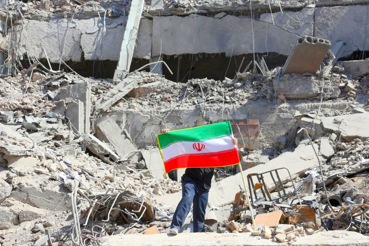 Un iraní coloca la bandera nacional de Irán entre las ruinas de una comisaría de policía dañada en el centro de Teherán, Irán. Foto: EFE/ Abedin Taherkenareh