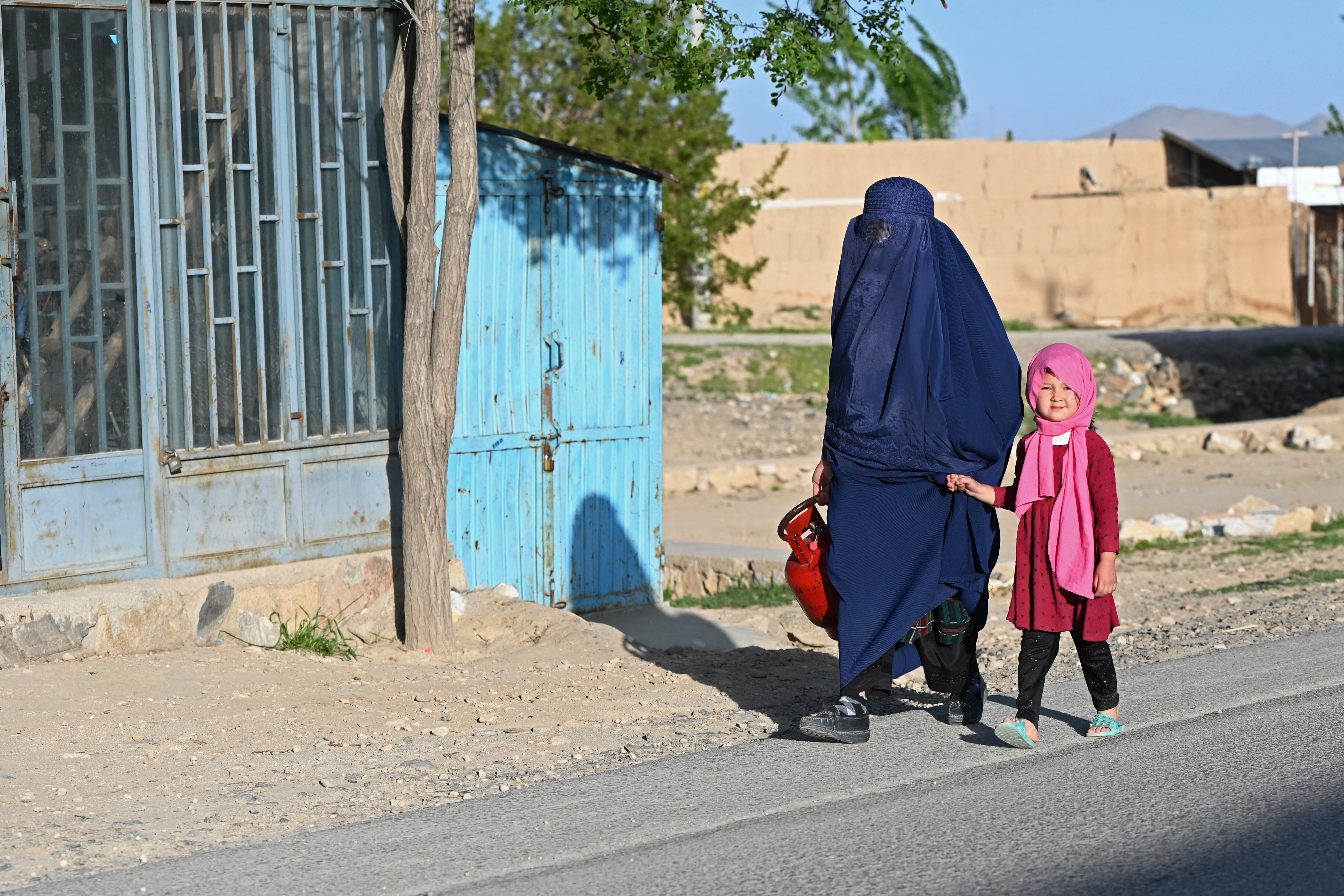 Una mujer afgana vestida con burka camina con una niña por una calle de Ghazni el 12 de mayo de 2024. (Foto de Wakil Kohsar / AFP)