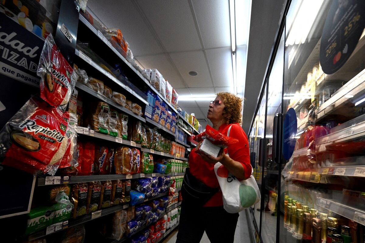 Una mujer mira los precios de los productos en un supermercado de Buenos Aires el 13 de diciembre de 2023. (Foto de Luis ROBAYO / AFP)