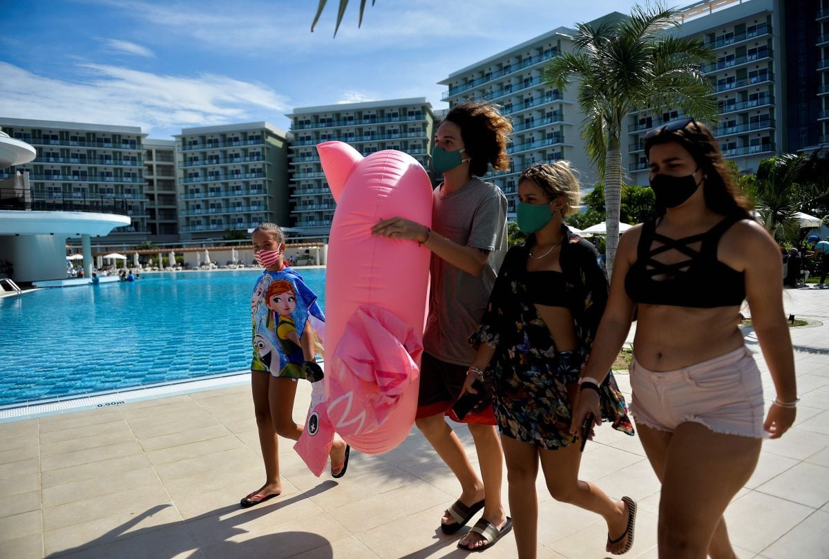 Una familia pasea junto a la piscina del Hotel Internacional Varadero, en la provincia de Matanzas, el 23 de octubre de 2020. Varadero, el balneario más importante de Cuba, está reabriendo al turismo internacional en medio de la pandemia del coronavirus. (AFP/YAMIL LAGE).