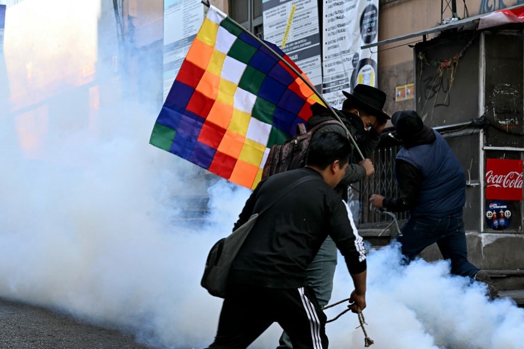 Manifestantes huyen para escapar de los gases lacrimógenos durante los enfrentamientos con la policía antidisturbios en una protesta que exige la renuncia del presidente boliviano Rodrigo Paz, en La Paz, el 18 de mayo de 2026. (Foto de AIZAR RALDES / AFP)