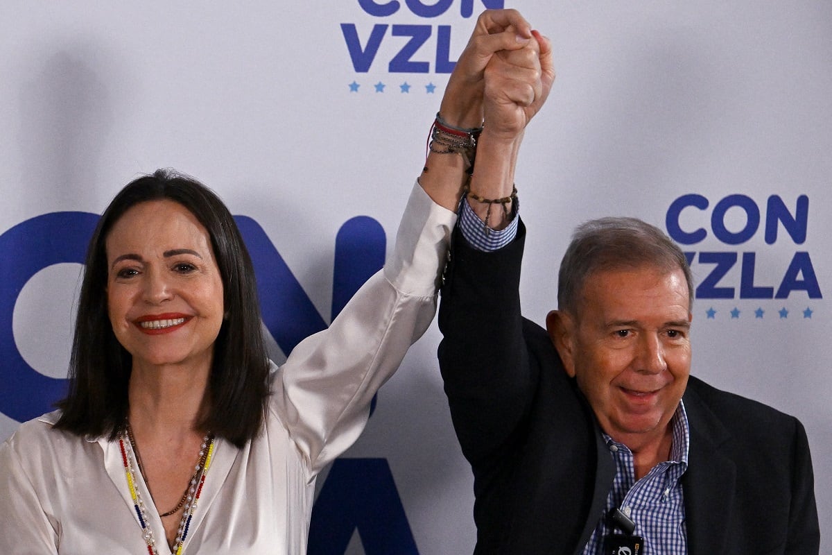 La líder de la oposición venezolana, María Corina Machado, levanta la mano del candidato presidencial de la oposición, Edmundo González Urrutia, en Caracas el 29 de julio de 2024. (Foto de JUAN BARRETO / AFP)