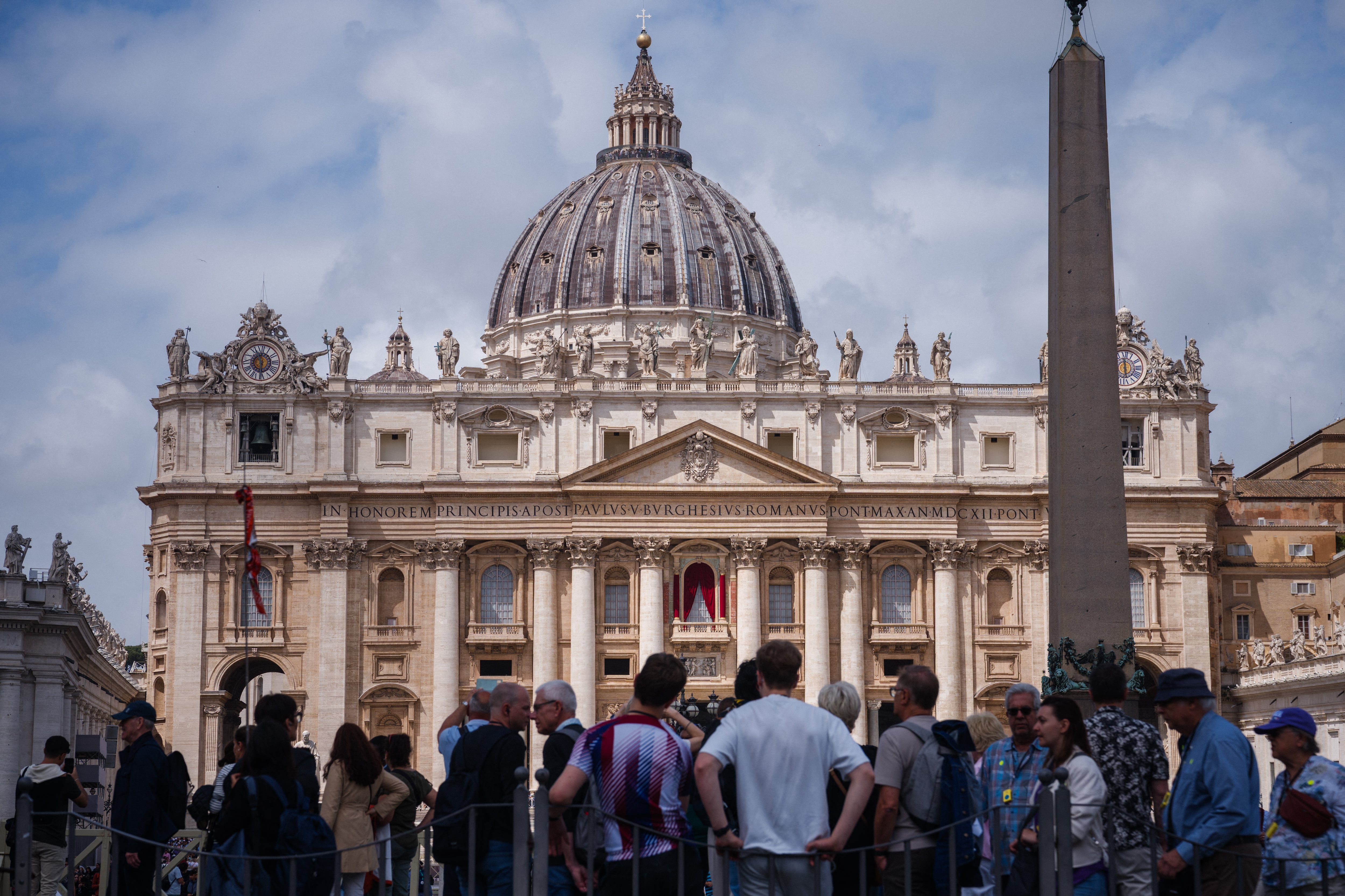 Visitantes caminan por la Plaza de San Pedro con la Basílica de San Pedro al fondo en el Vaticano, tomada desde Roma el 5 de mayo de 2025. (Foto de Dimitar DILKOFF / AFP)