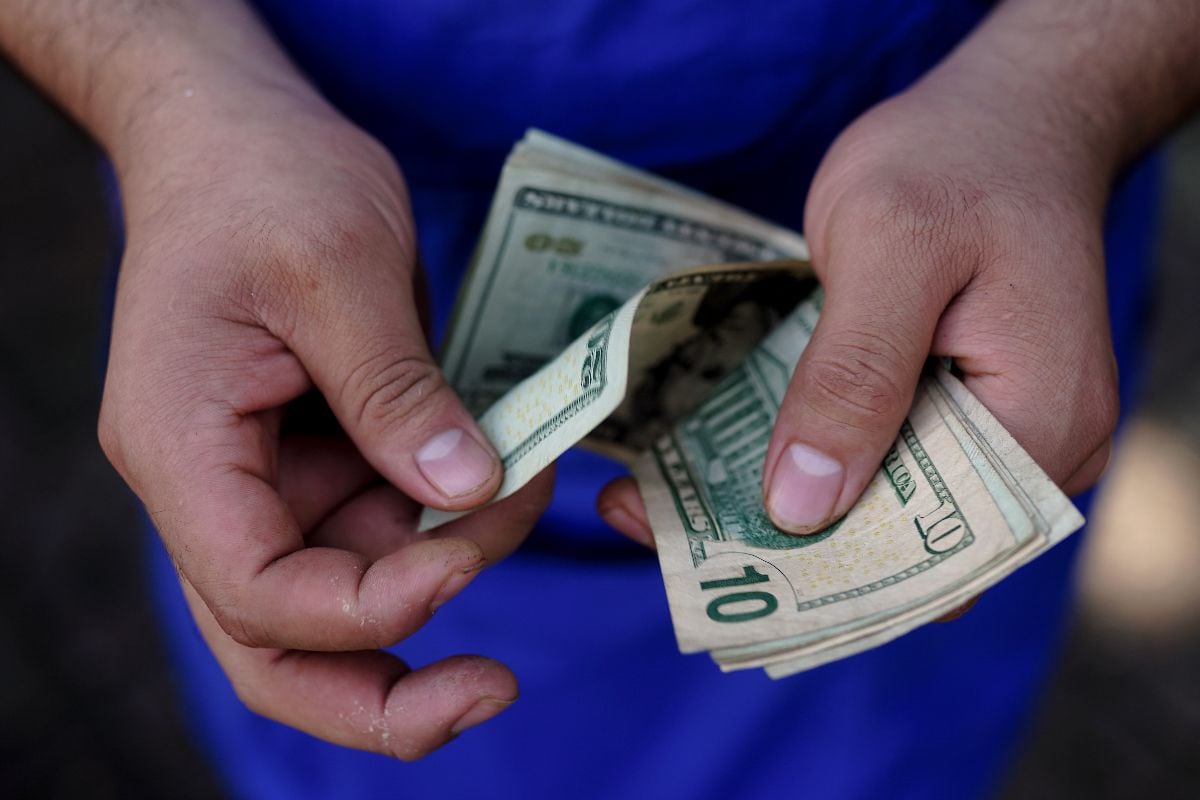 A vendor counts US dollar banknotes during a food wholesale event at Plaza Centenario in Quezaltepeque, La Libertad department, El Salvador, on Tuesday, July 9, 2024. El Salvador President Nayib Bukele said during a televised cabinet meeting over the weekend that food importers, wholesalers and retailers must lower prices or face criminal investigations for alleged bribery, tax evasion and contraband smuggling. Photographer: Camilo Freedman/Bloomberg