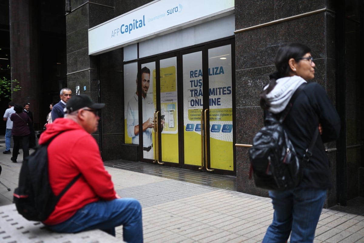 Personas esperan fuera de las oficinas de AFP Capital, una administradora privada de fondos de pensiones, en Santiago, el 26 de octubre de 2026. Las administradoras de fondos de pensiones (AFP) chilenas han registrado pérdidas multimillonarias, vinculadas principalmente a operaciones de permuta financiera (swaps) de tasas de interés en el Fondo E, lo que afecta a más de 760,000 afiliados, incluidos más de 69,000 mayores de 60 años. El Fondo E, el más conservador de los cinco fondos disponibles en el sistema, fue el más perjudicado, con una caída promedio del 10.4% entre enero y septiembre de 2026. (Foto de Rodrigo ARANGUA / AFP)