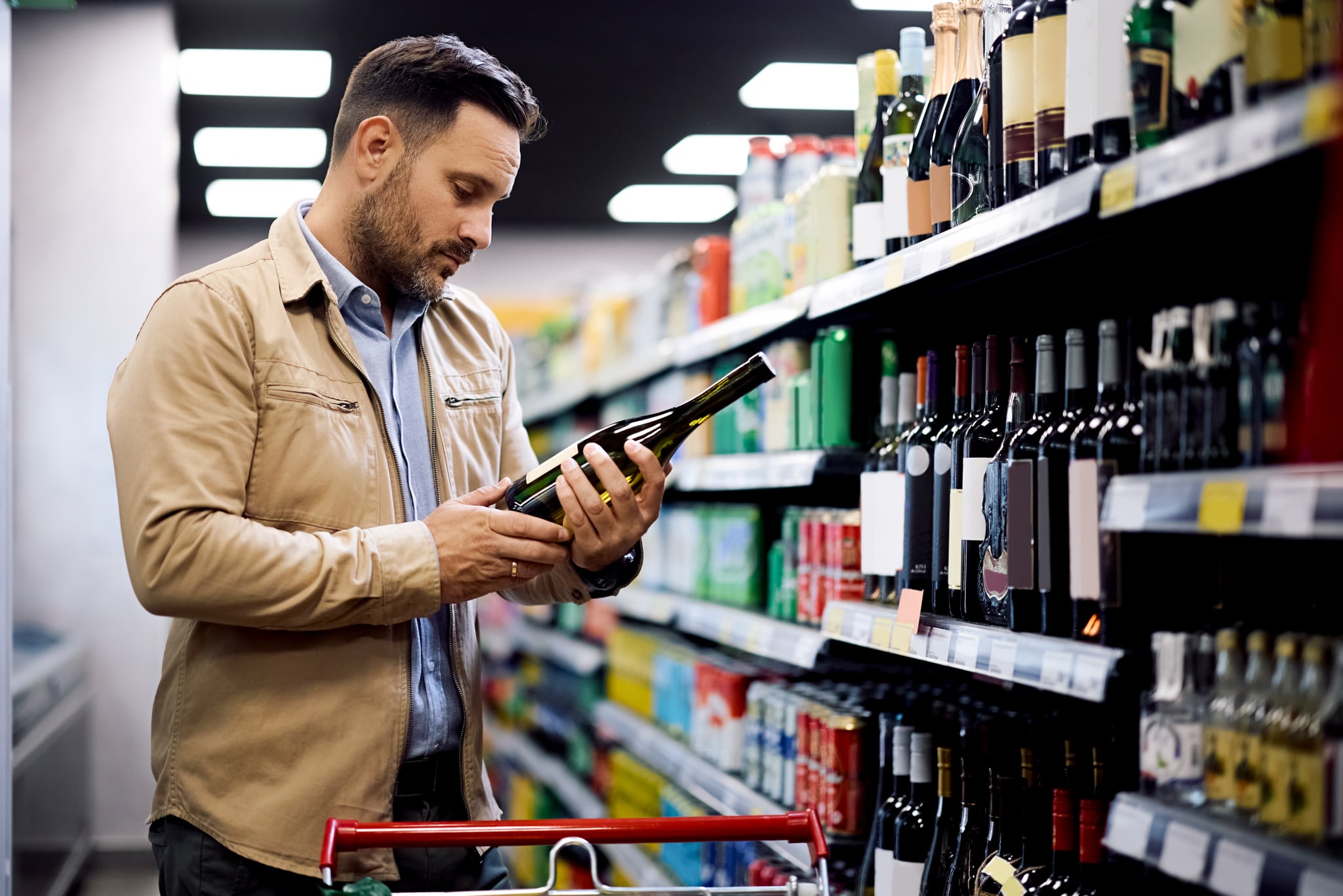 Mid adult man choosing wine while shopping at the store.