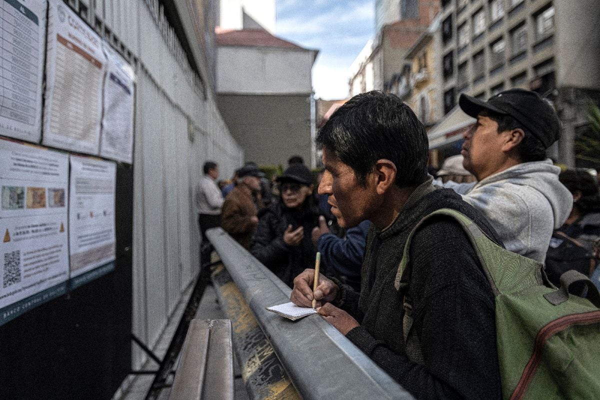 Un hombre toma notas de un panel de información oficial sobre qué billetes son válidos y cuáles no, frente al Banco Central de Bolivia en La Paz el 3 de marzo.