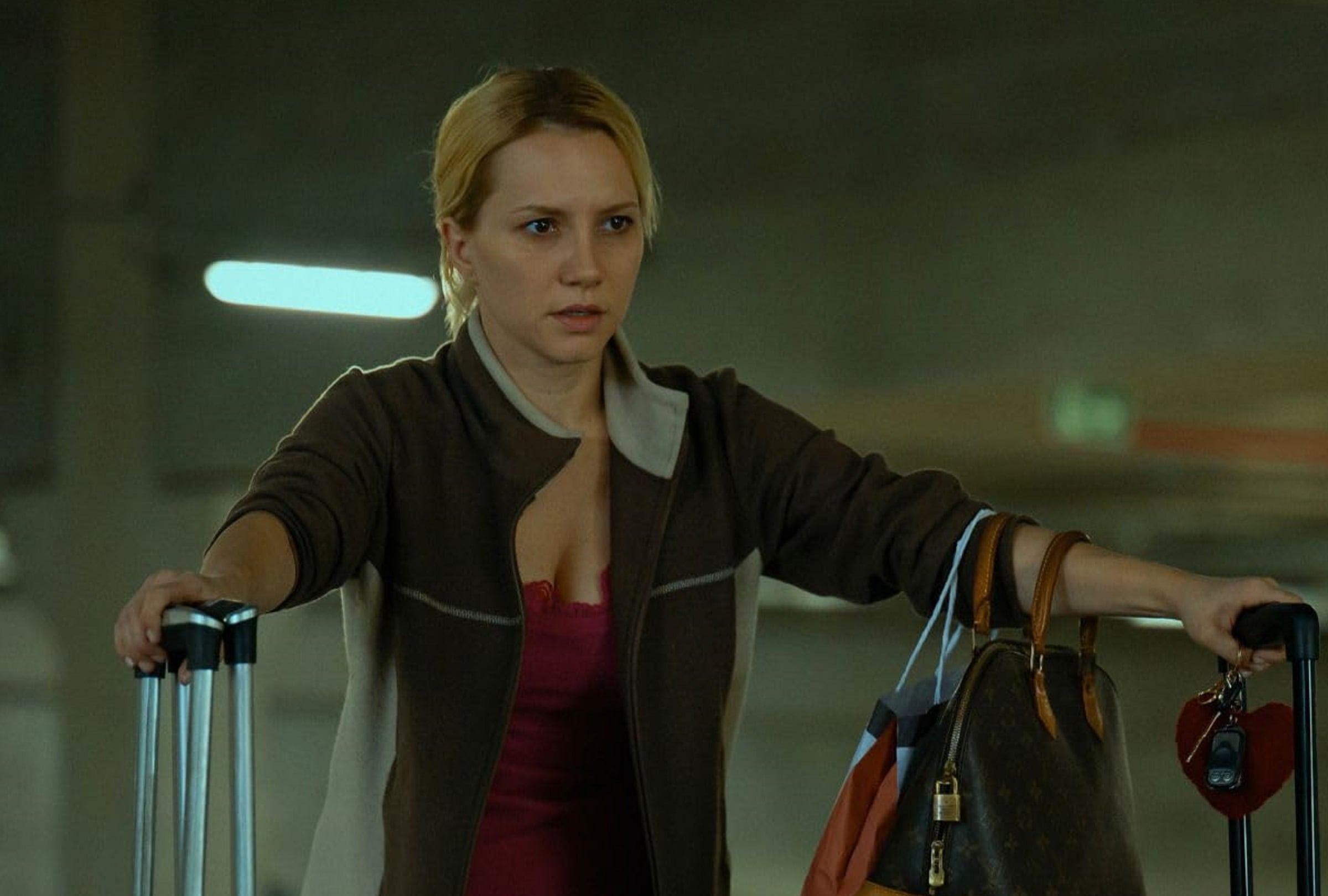 Elize (Lorena Comparato) saliendo de su departamento con varias maletas luego de asesinar a su esposo en la película brasileña "Elize: Sombras de una mujer" (Foto: Netflix)