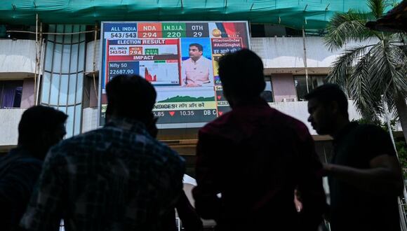 Peatones observan los precios de las acciones en una transmisión digital fuera de la Bolsa de Valores de Bombay. Fotógrafo: Punit Paranjpe/AFP/Getty Images