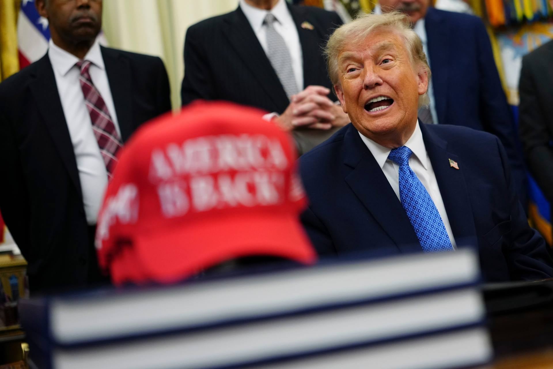 El presidente de Estados Unidos, Donald Trump, habla junto a una gorra roja que dice, en inglés, “¡Estados Unidos está de regreso!”, en el Despacho Oval de la Casa Blanca, el viernes 26 de junio de 2026, en Washington. (AP Foto/Julia Demaree Nikhinson)